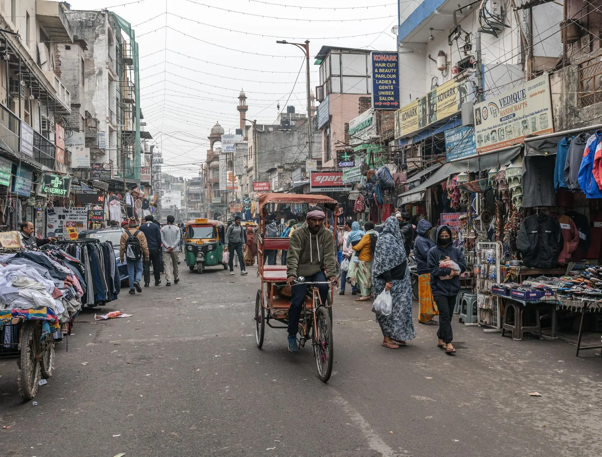 Vibrant street scene in New Delhi with people, shops, and a rickshaw in a busy marketplace