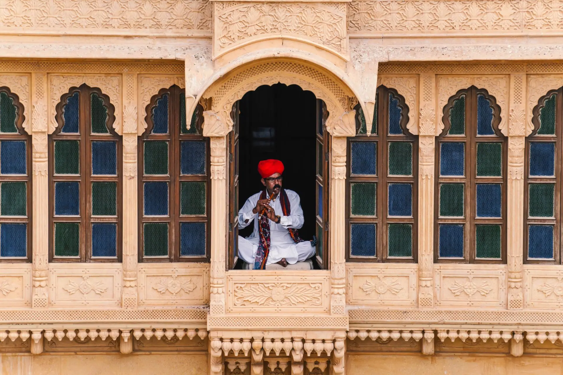 Rajasthani musician playing a flute in a traditional jharokha in Jaisalmer, India