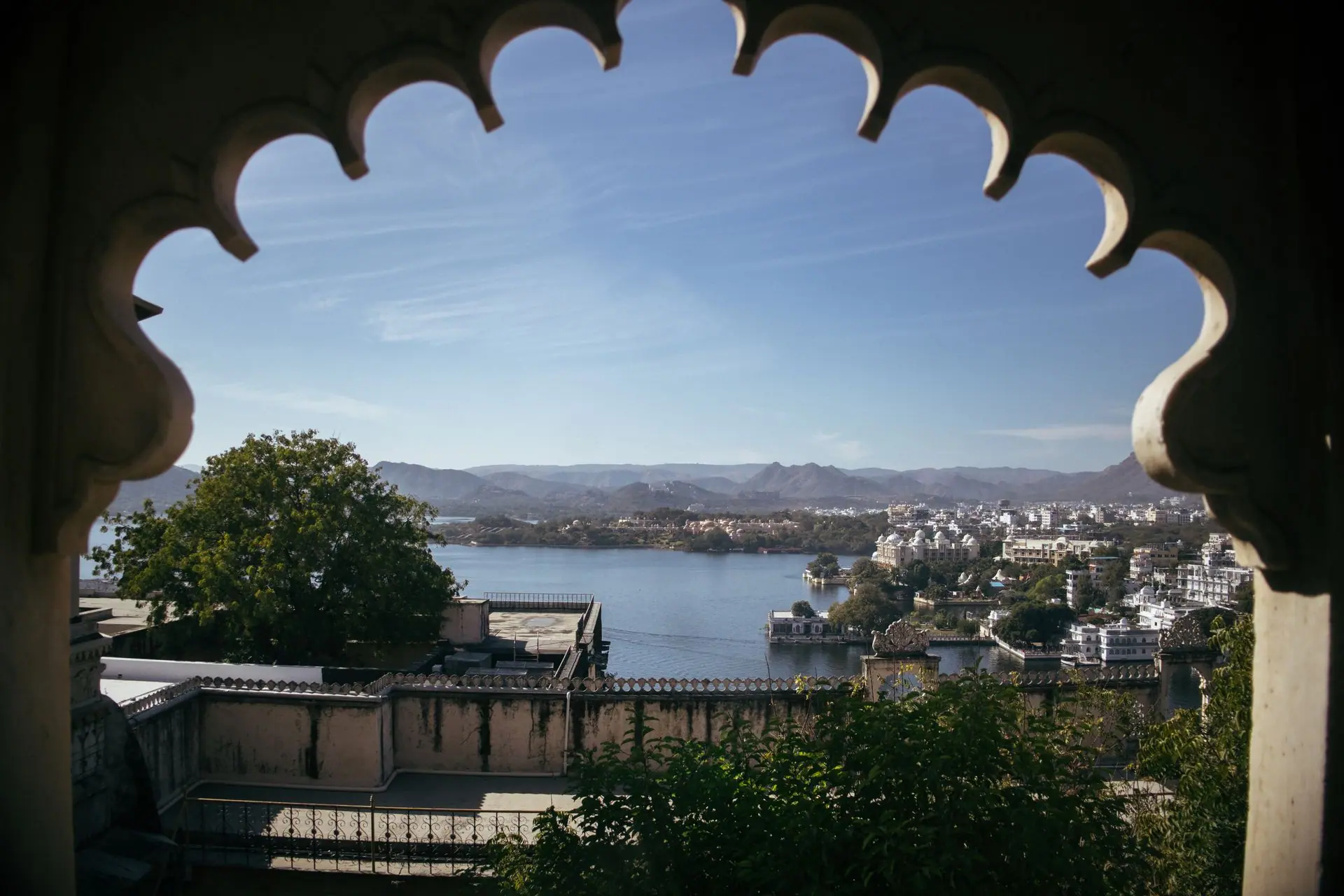 Breathtaking view of Udaipur city through a decorative archway, showcasing Lake Pichola and surrounding architecture