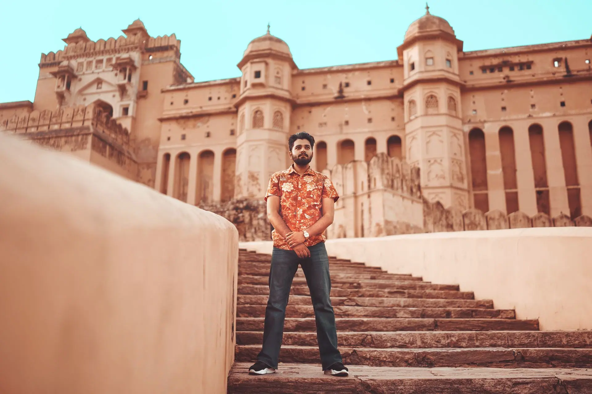 Man standing on steps of historic Amber Fort in Jaipur, Rajasthan, showcasing its grandeur and medieval architecture