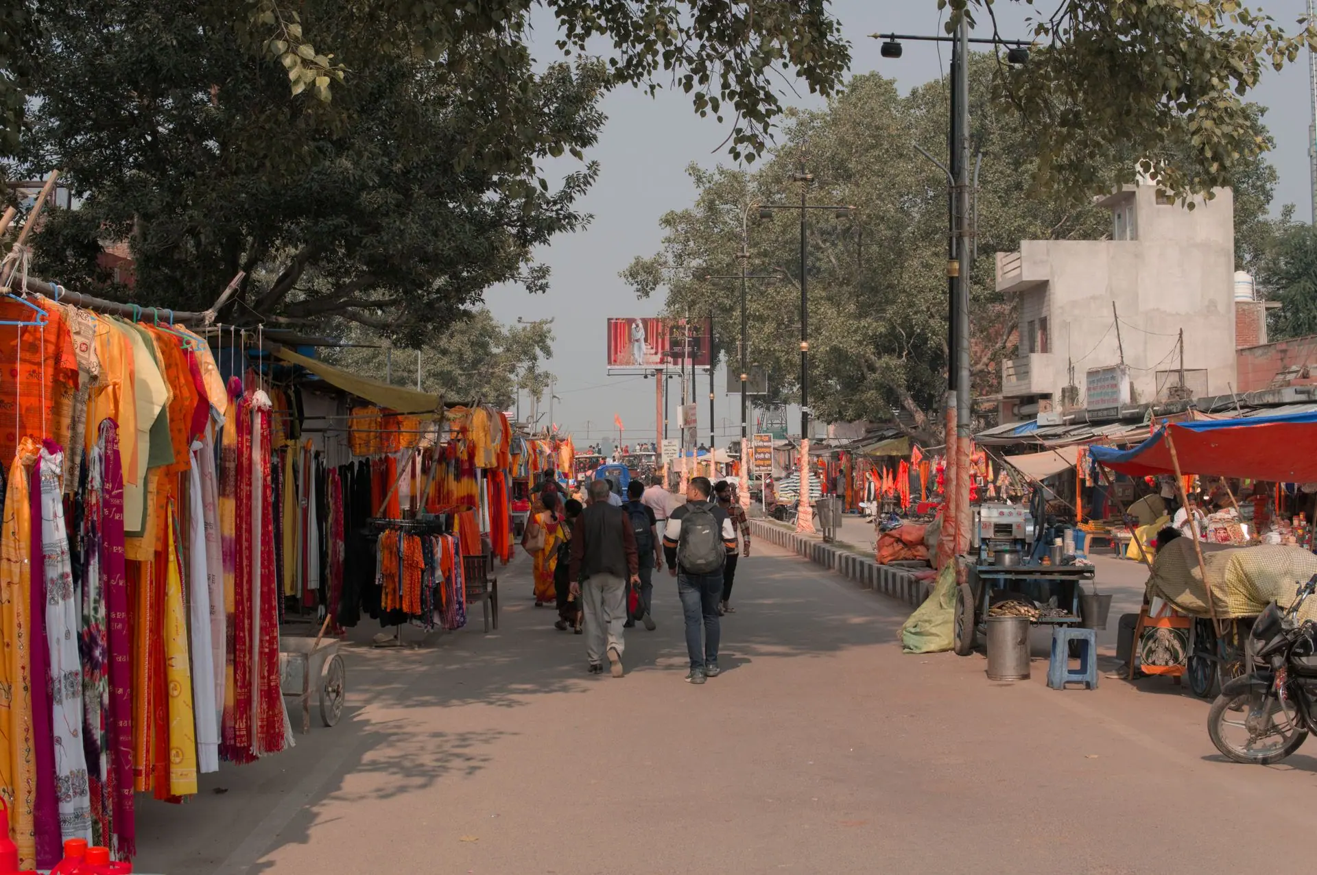 A bustling street market in Ayodhya with colorful textiles and people during the day