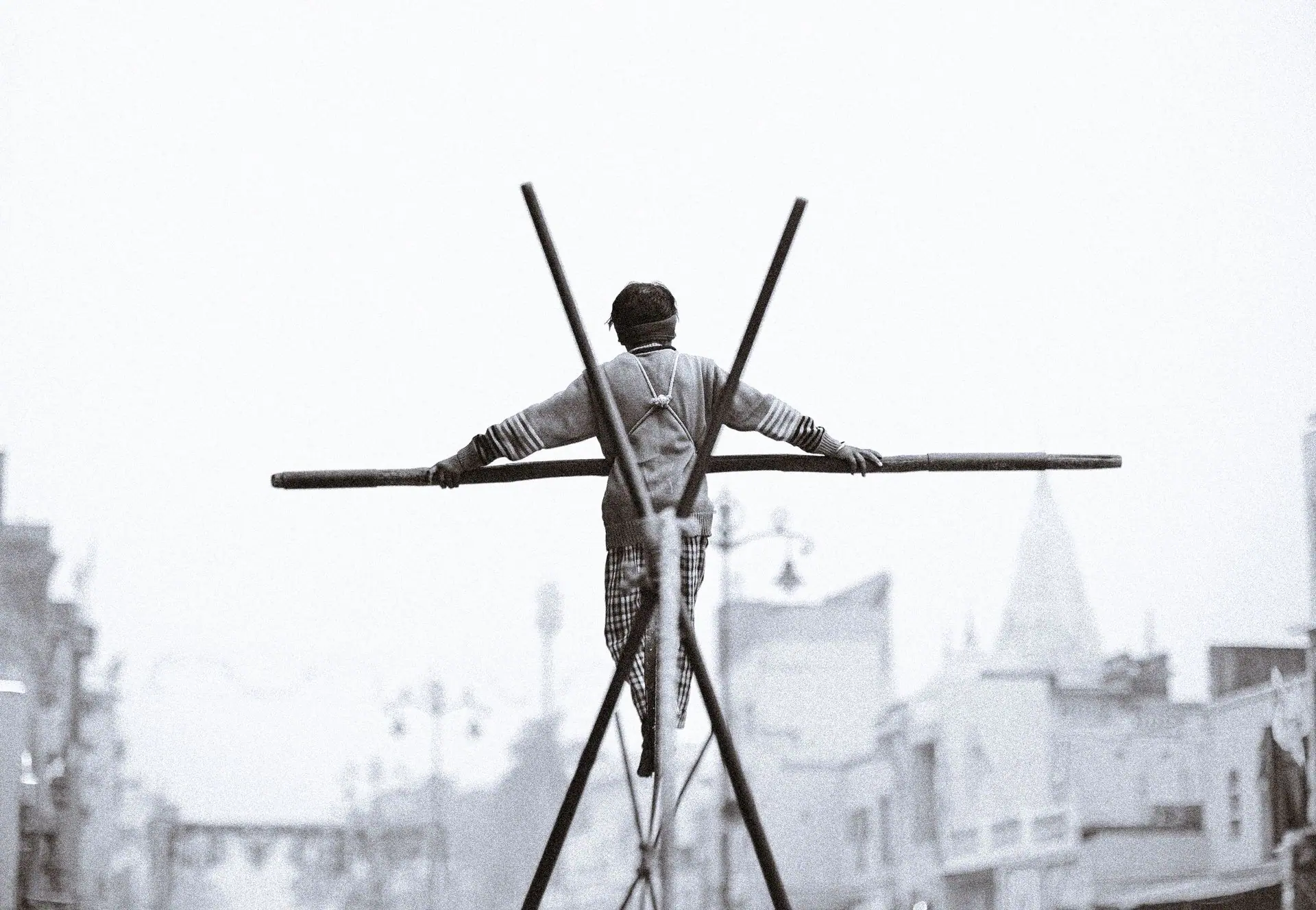 A dramatic scene of a man balancing on a tightrope in Ayodhya, capturing the urban backdrop and traditional street performance