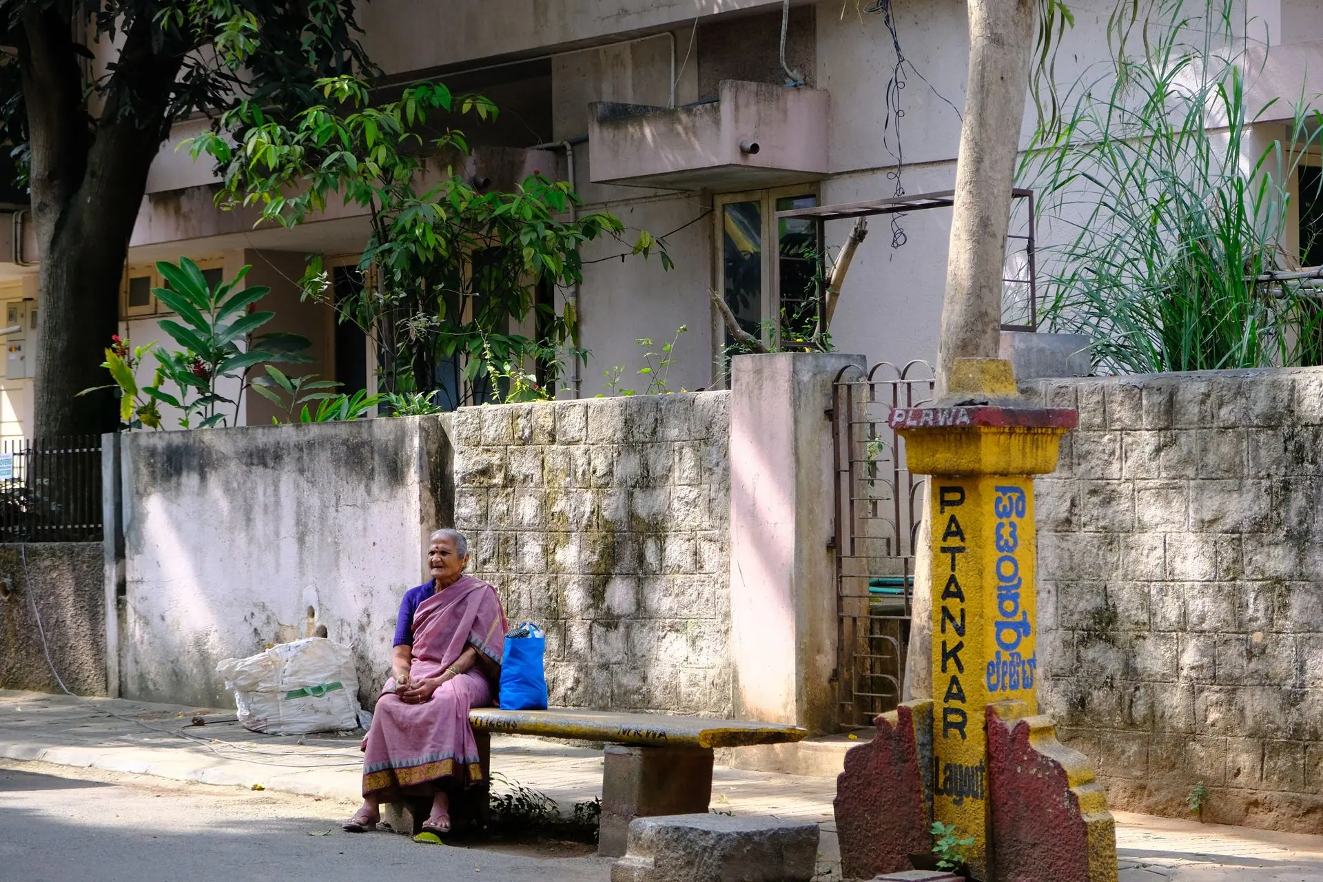 Senior woman in traditional saree sitting on a bench outdoors in Bengaluru