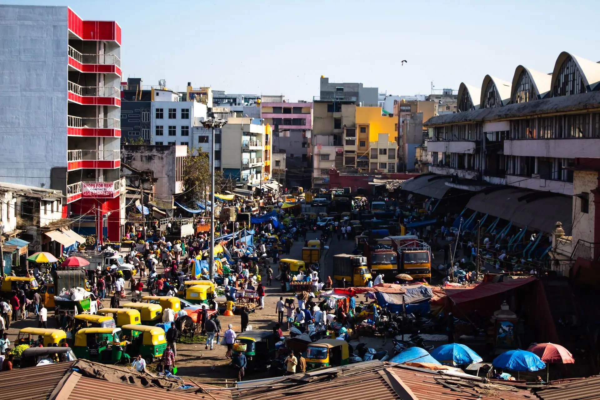 Bustling street scene in Bengaluru, India with colorful vehicles and vibrant market activity