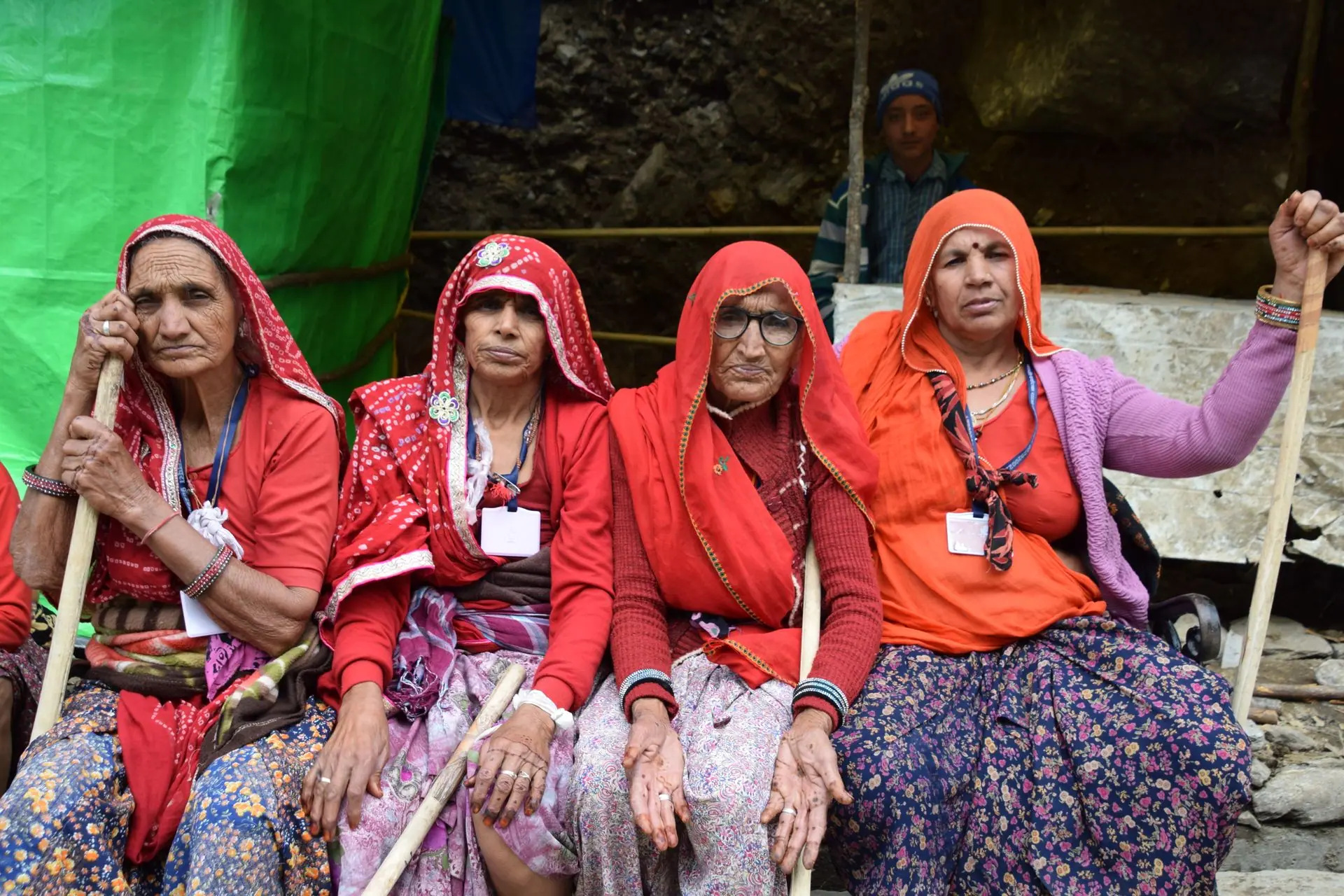 Four elderly Indian women pilgrims in traditional attire seated outdoors in Kedarnath, India
