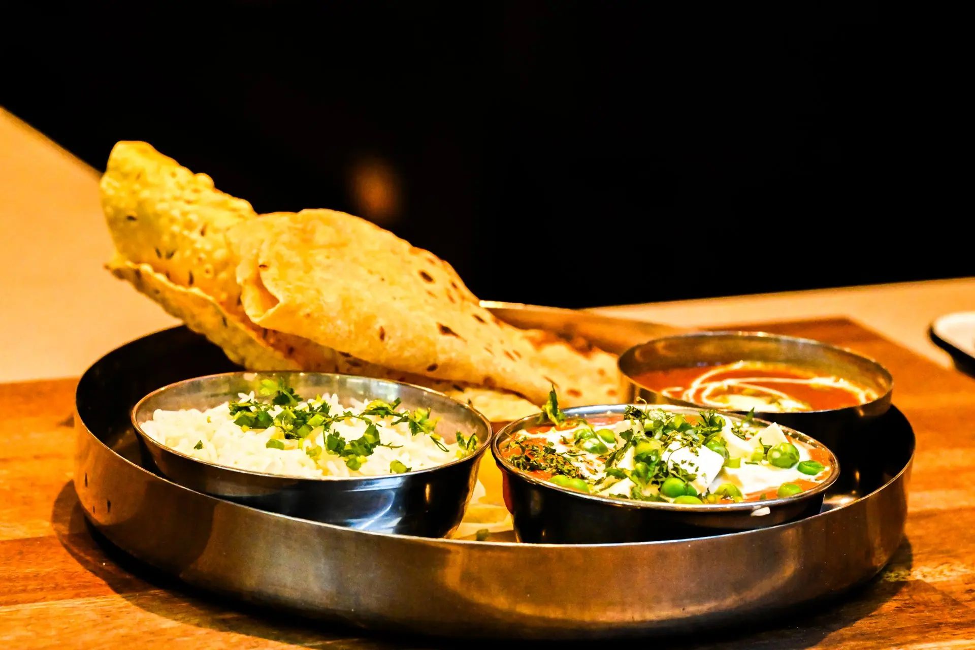 Exquisite Indian thali with naan bread, paneer curry, and aromatic rice served on a wooden table