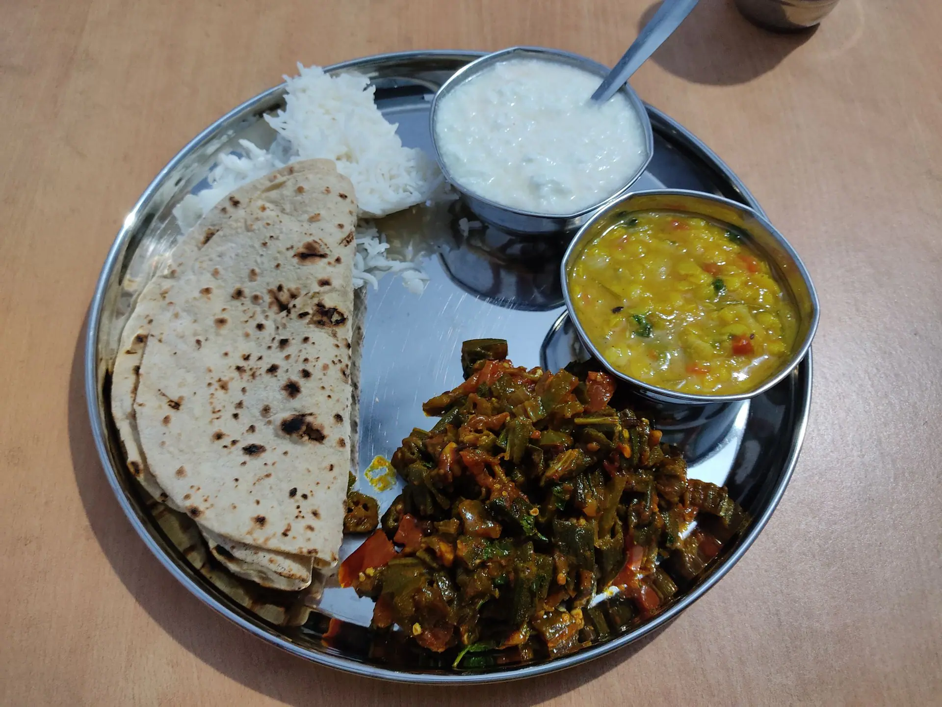 Delicious Indian thali with chapati, rice, dal, okra, and yogurt. A traditional vegetarian meal