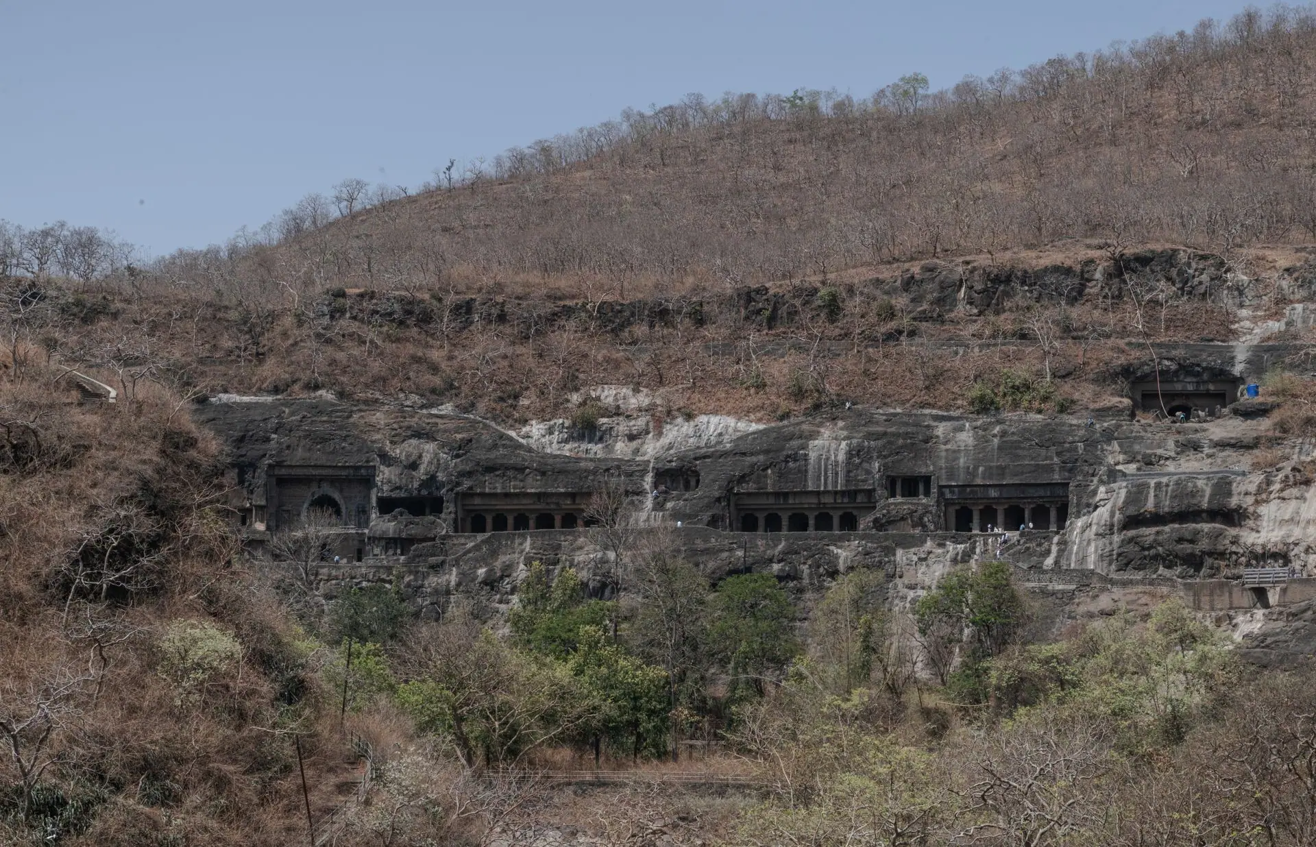 Ajanta Caves in Maharashtra, India carved into dry mountain landscape under clear sky