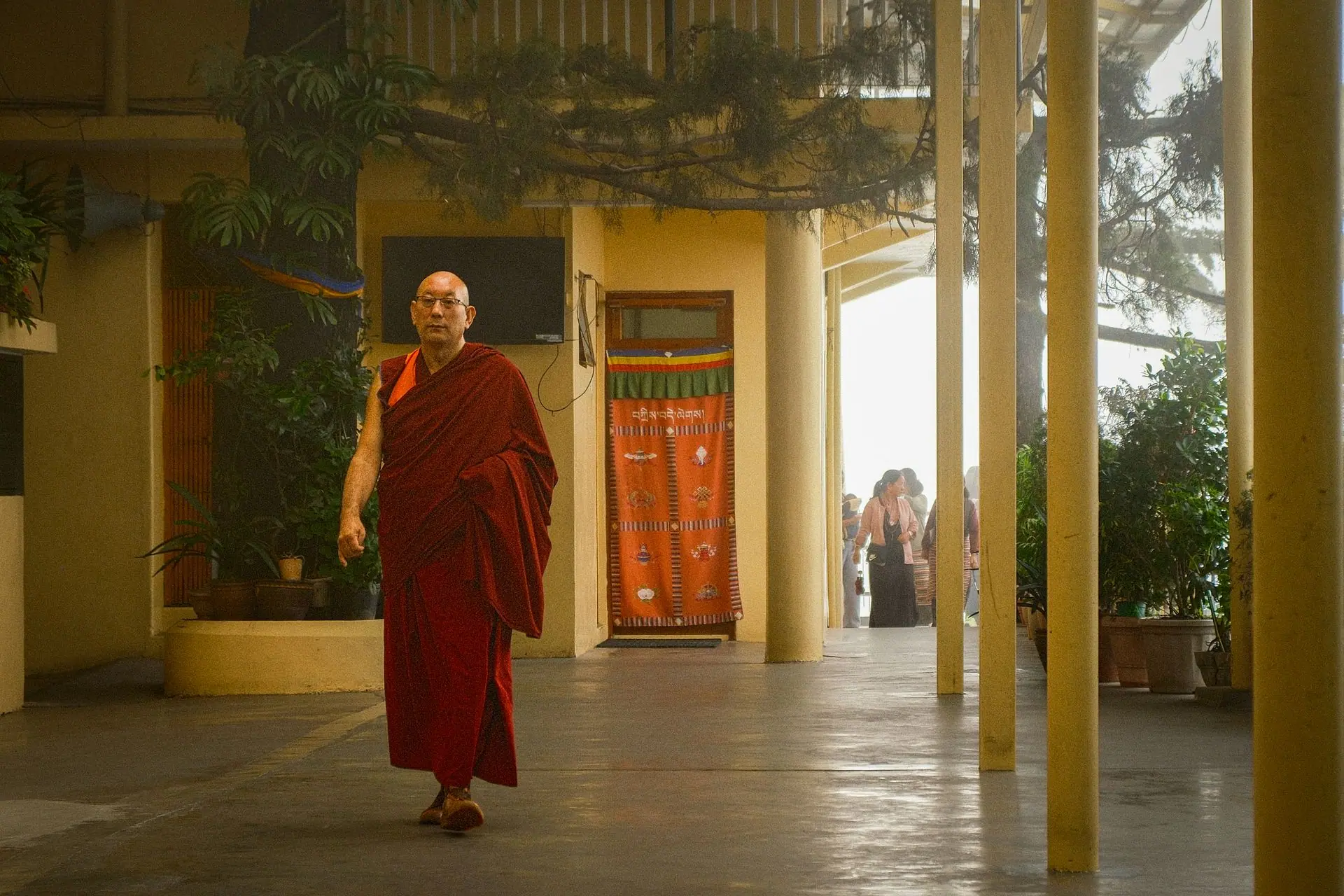 A Buddhist monk in traditional robe strolling inside a serene monastery in Dharamshala, India