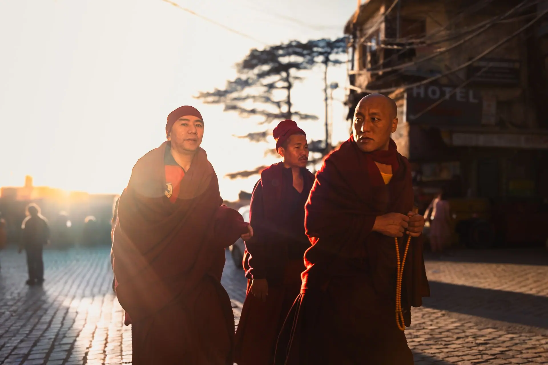 Monks in maroon robes walk through Dharamshala, India, at sunrise, creating a serene and spiritual atmosphere