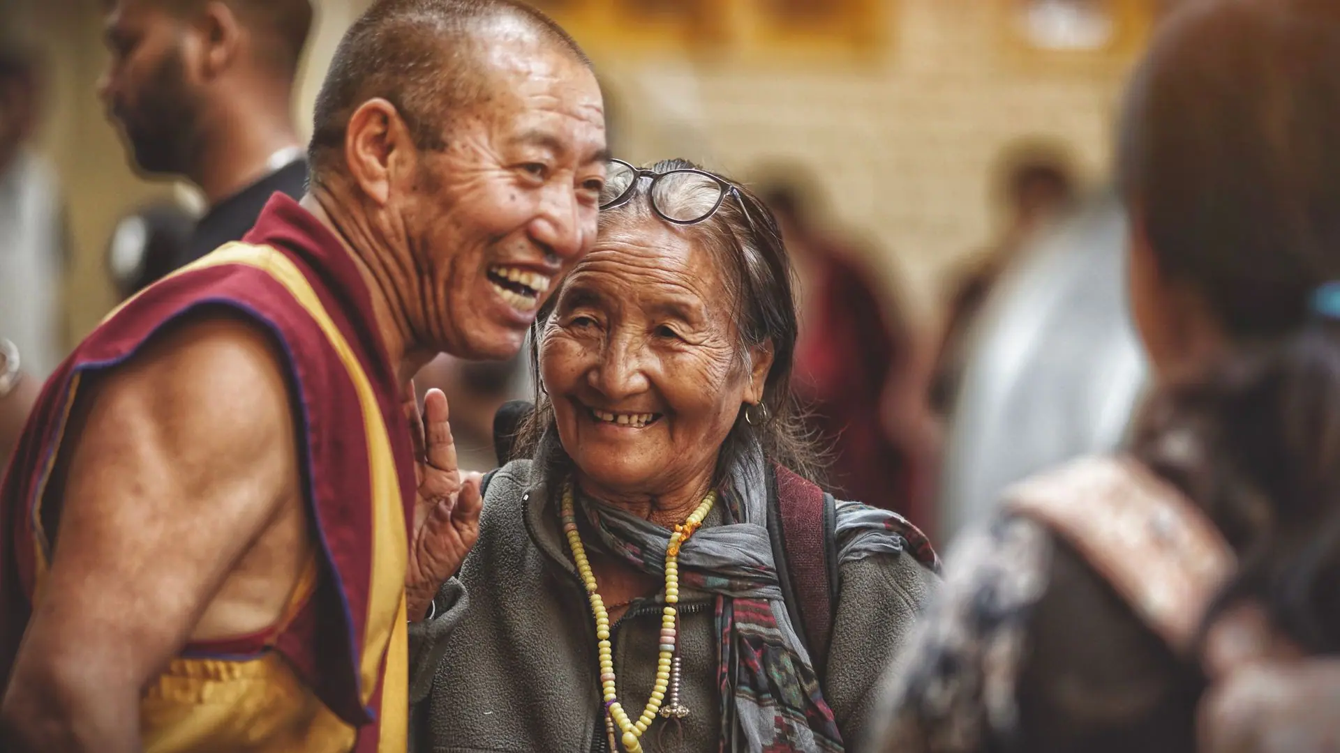 Smiling monk and elderly woman sharing a joyful moment in Dharamshala, India