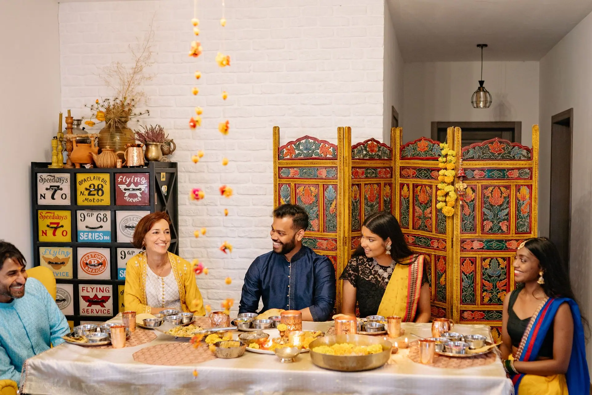 A joyful Indian family celebration with traditional clothing and festive foods, gathered around a dinner table