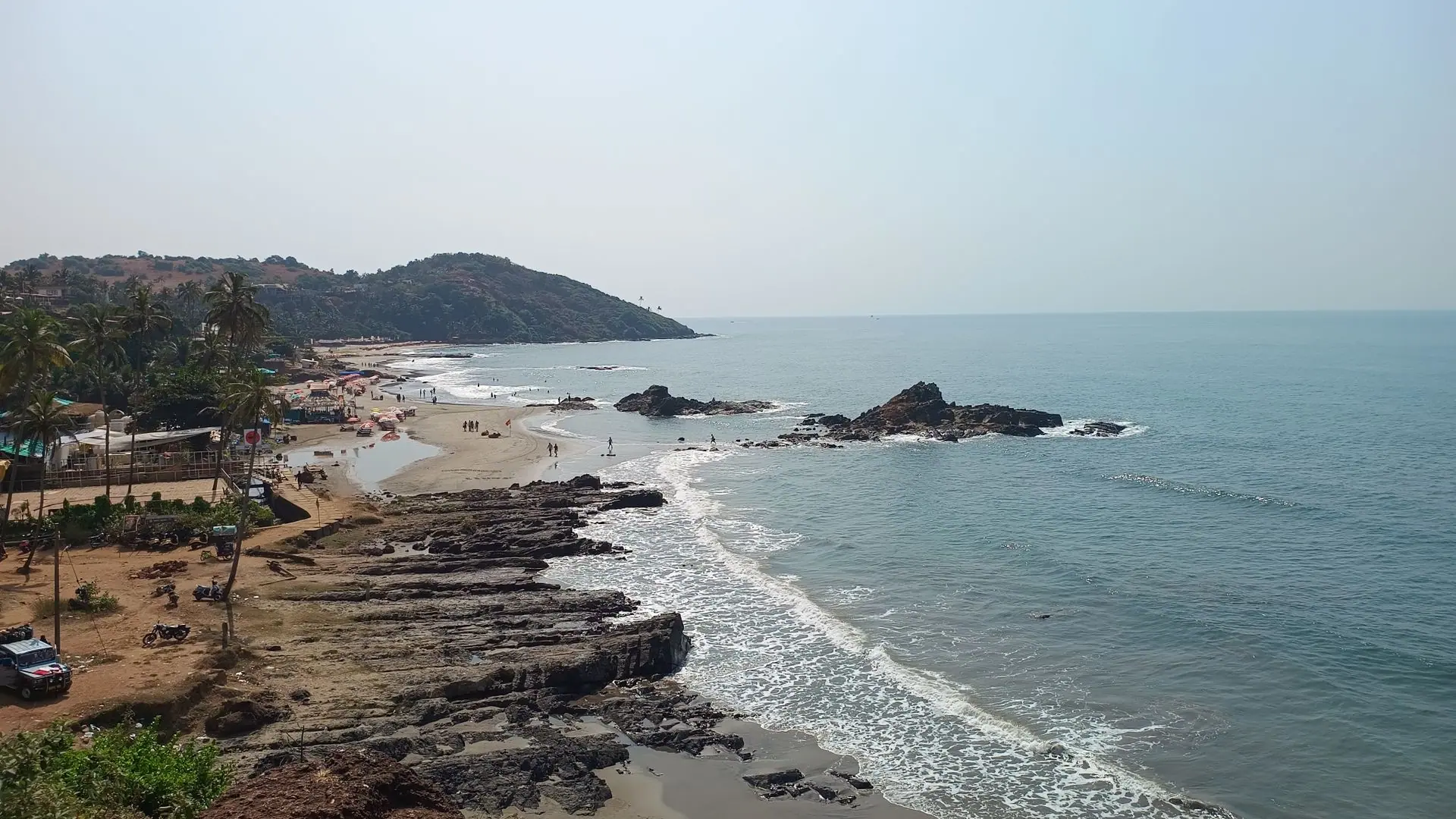 Explore the serene Anjuna Beach in Goa, showcasing beautiful sandy shores and rocky coastline