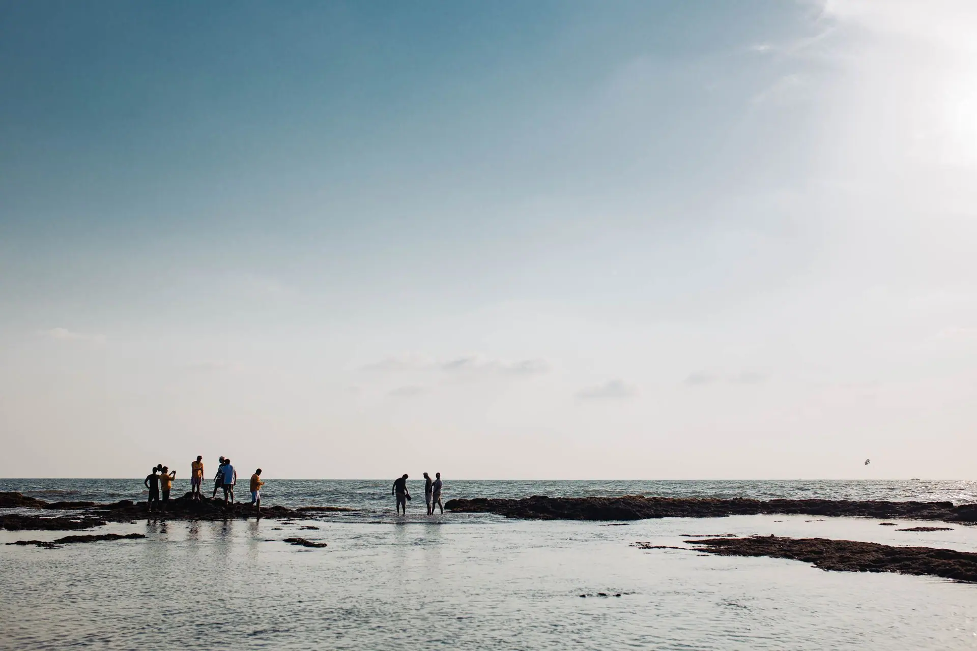 A group of people enjoying the serene ocean view at Baga Beach, India during sunset