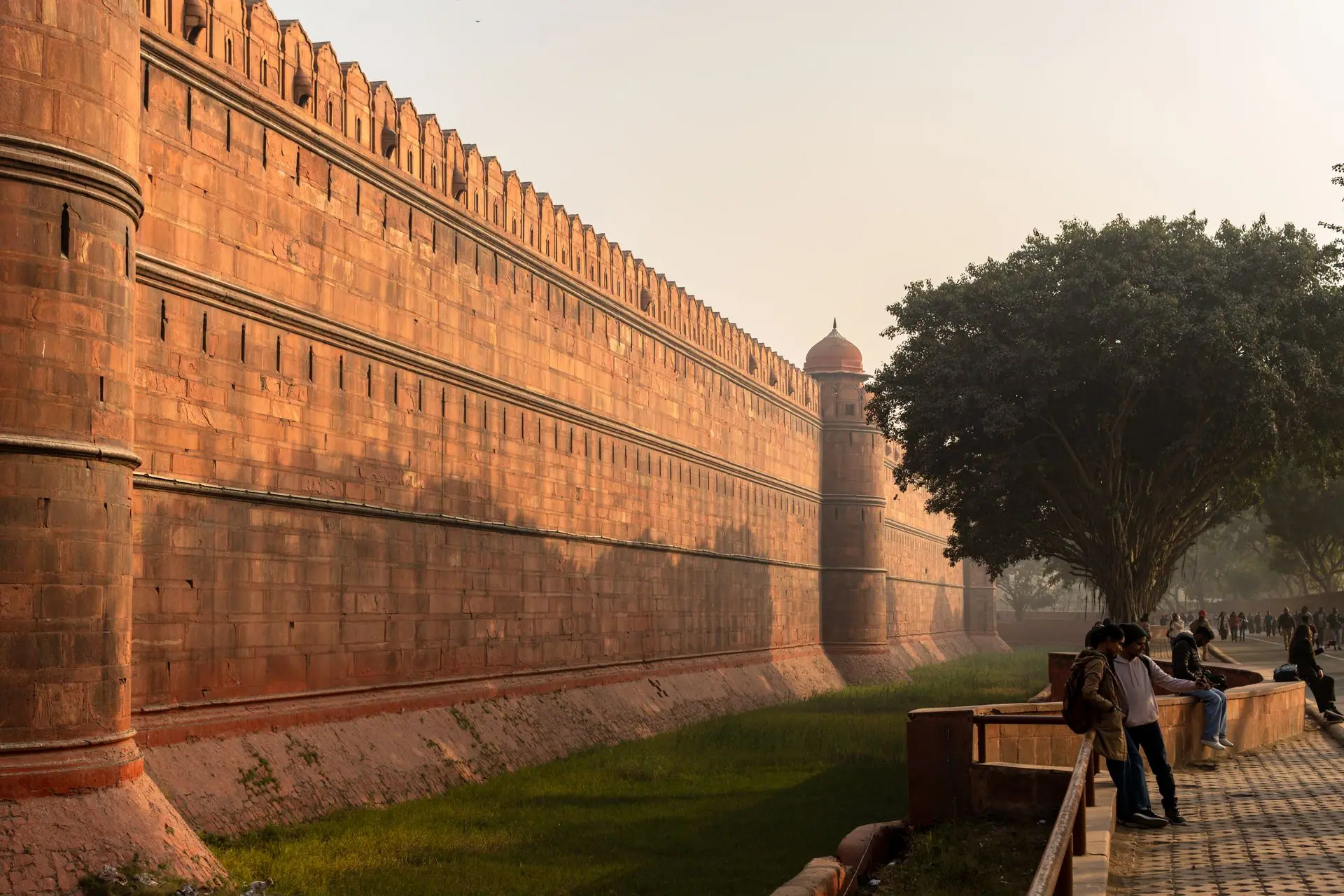 A view of the historic Red Fort in Delhi, India with people strolling nearby