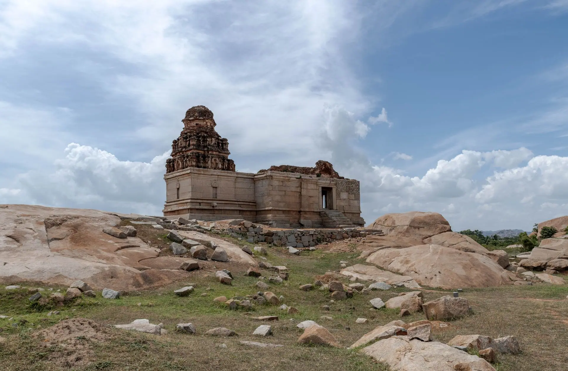Explore the ancient temple ruins in Hampi, India surrounded by rocky landscape and clear blue skies