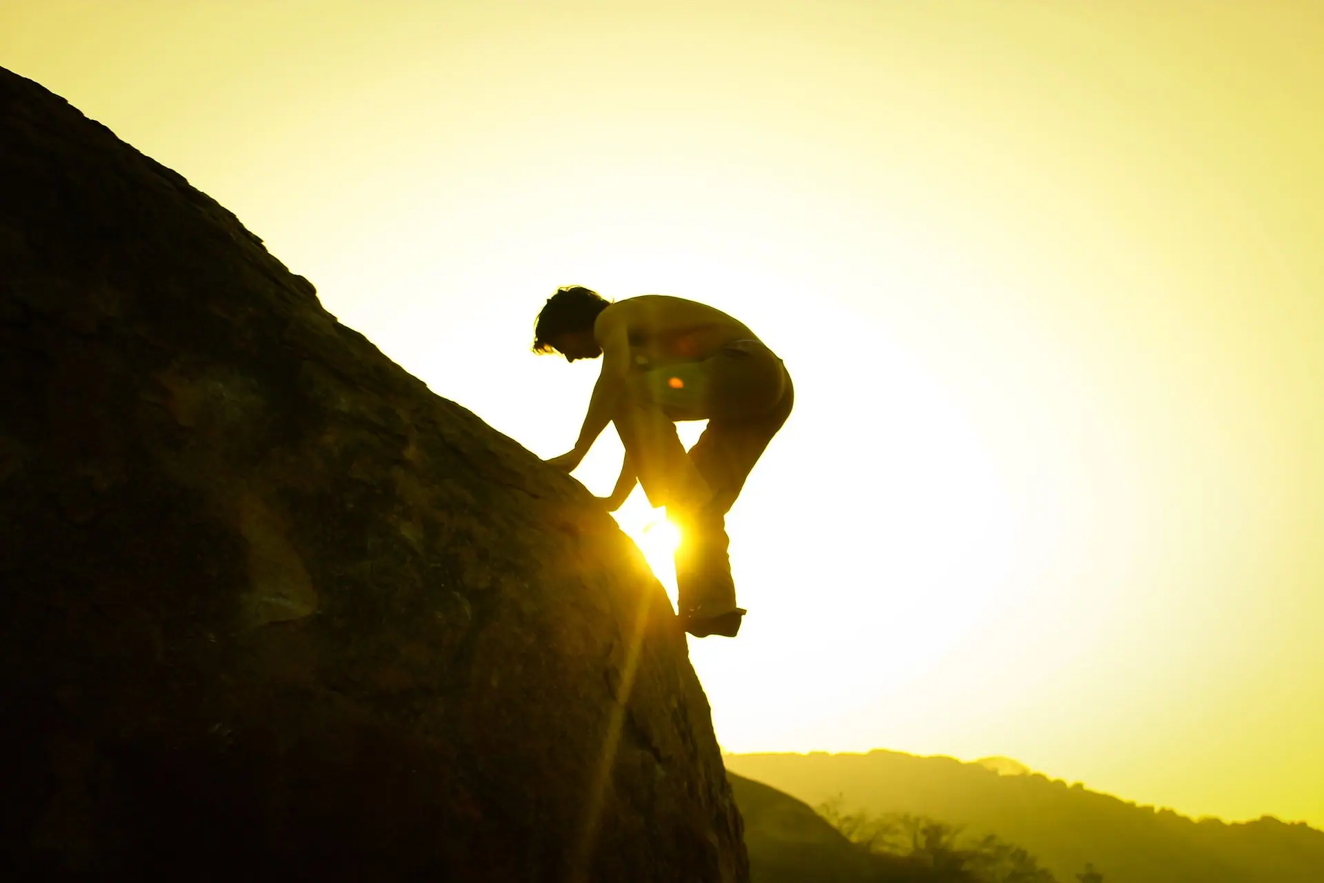 A silhouette of a climber ascending a rock in Hampi, India at sunrise
