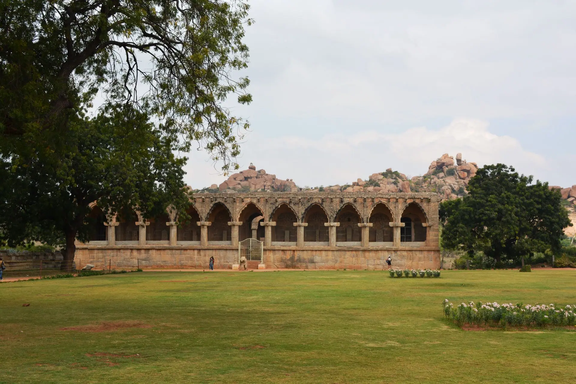 Historic stone building in Hampi, India, surrounded by lush greenery and unique rock formations