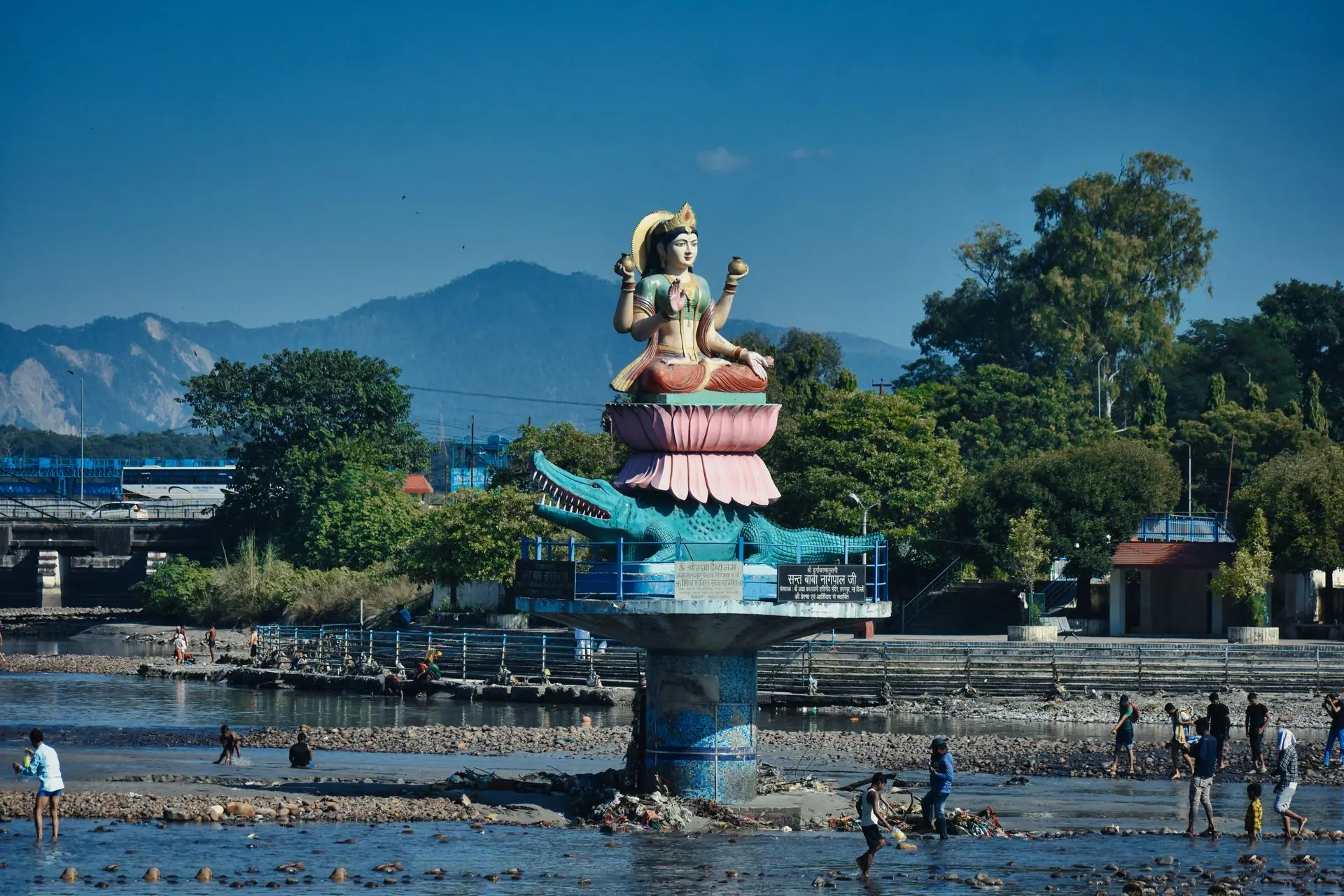 Statue of a goddess by the river in Haridwar, India, a scenic summer day with people around