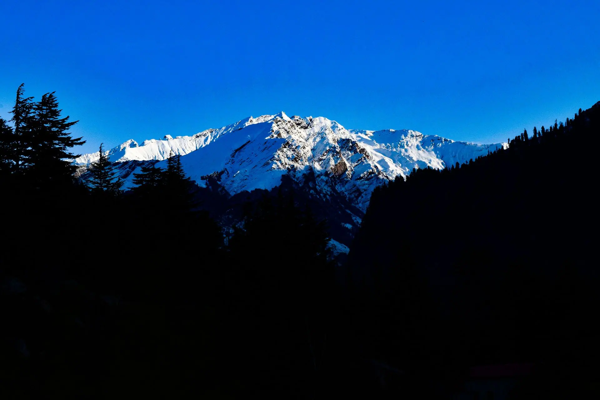 Majestic snowcapped mountains under a vibrant blue sky, captured in Manali, India