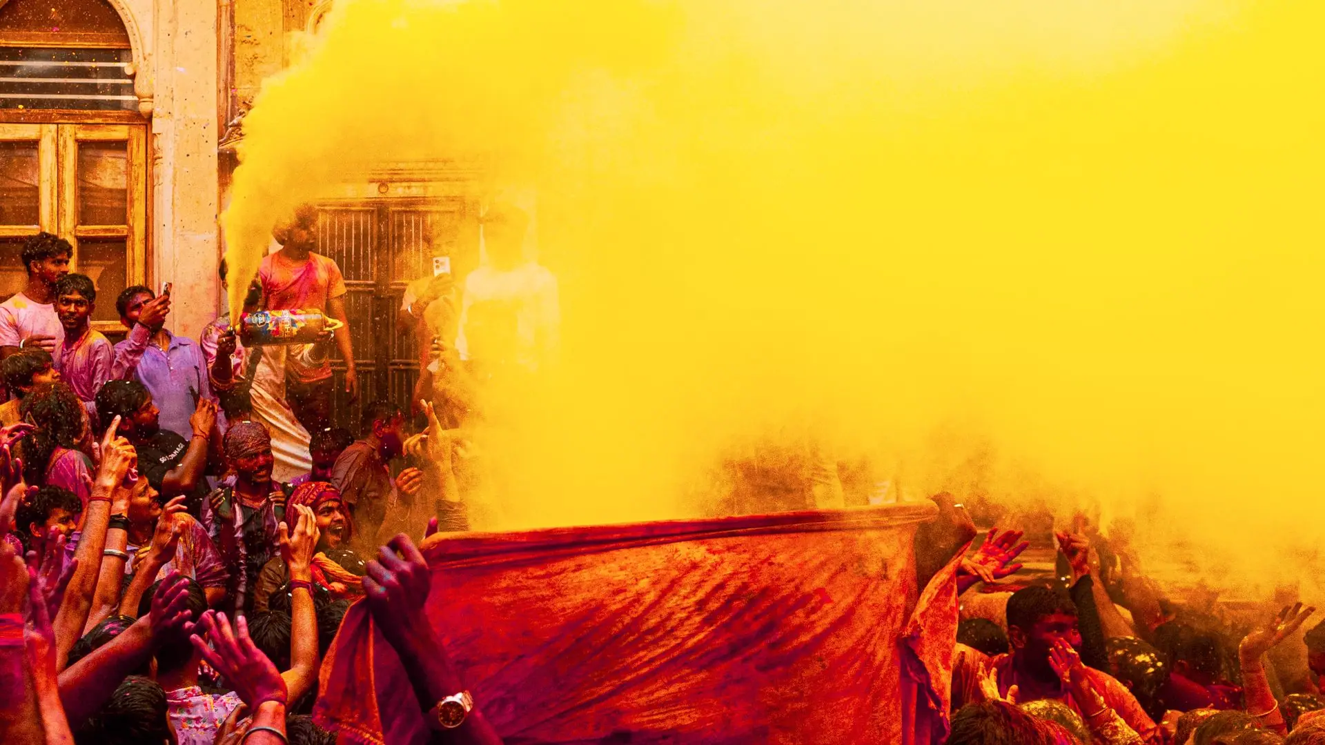 Dynamic scene from a Holi festival with vibrant yellow and red powders embracing the crowd in celebration