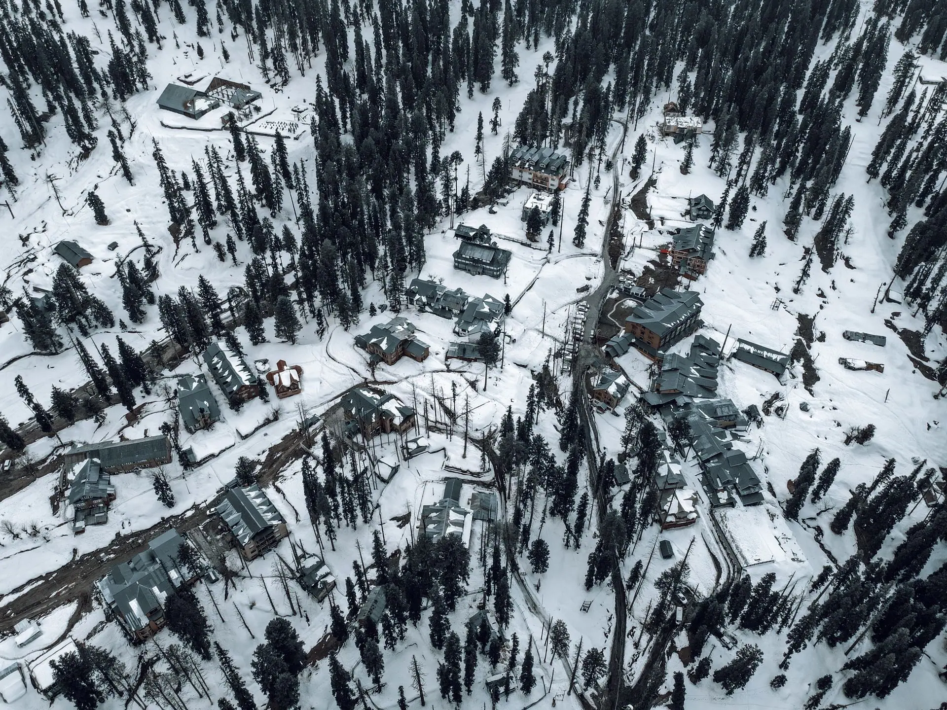 Snow-covered aerial view of Gulmarg, showcasing buildings and pine trees in winter
