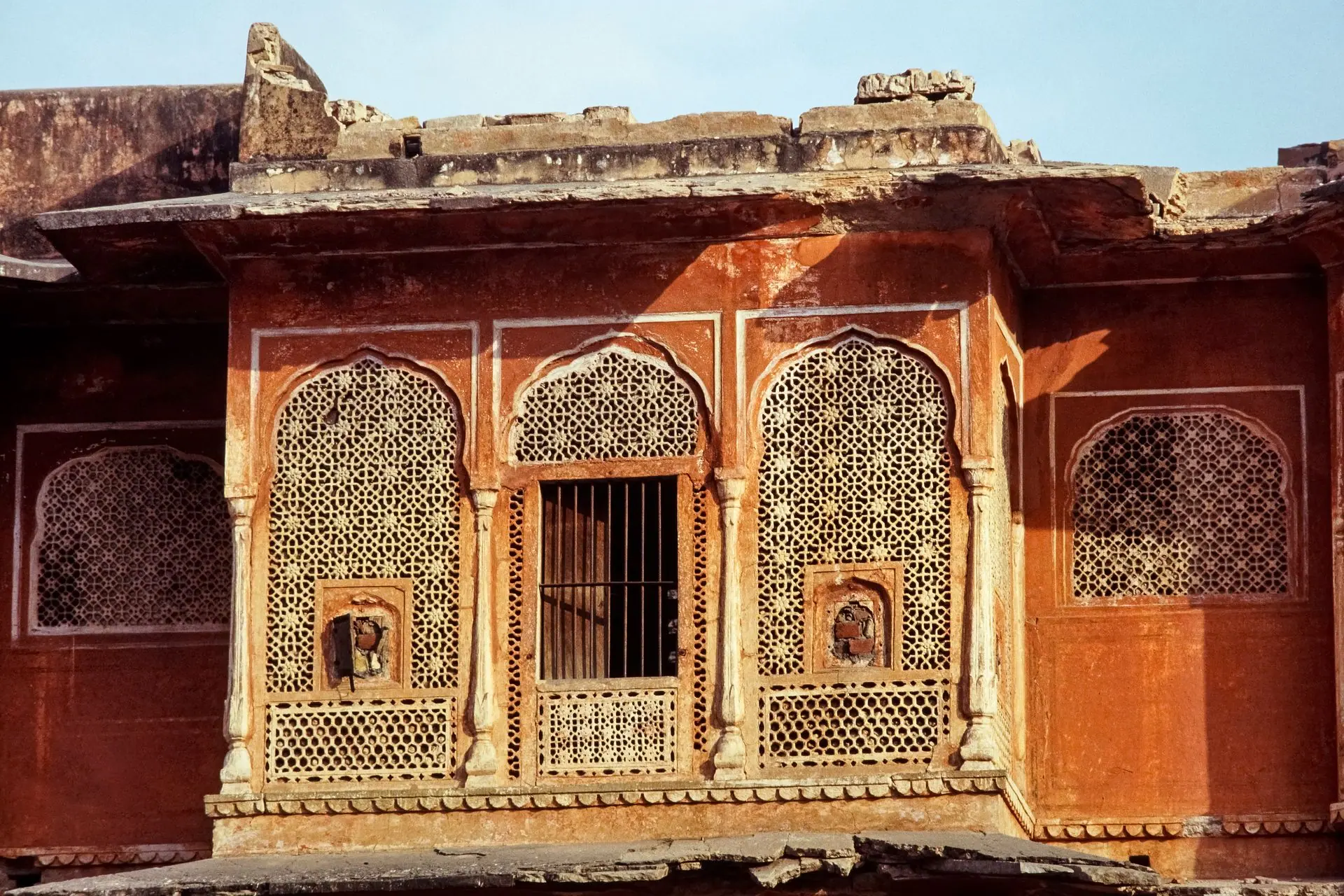 Detailed view of the ornate lattice windows of a historic Jaipur palace, showcasing classic Indian sandstone artistry