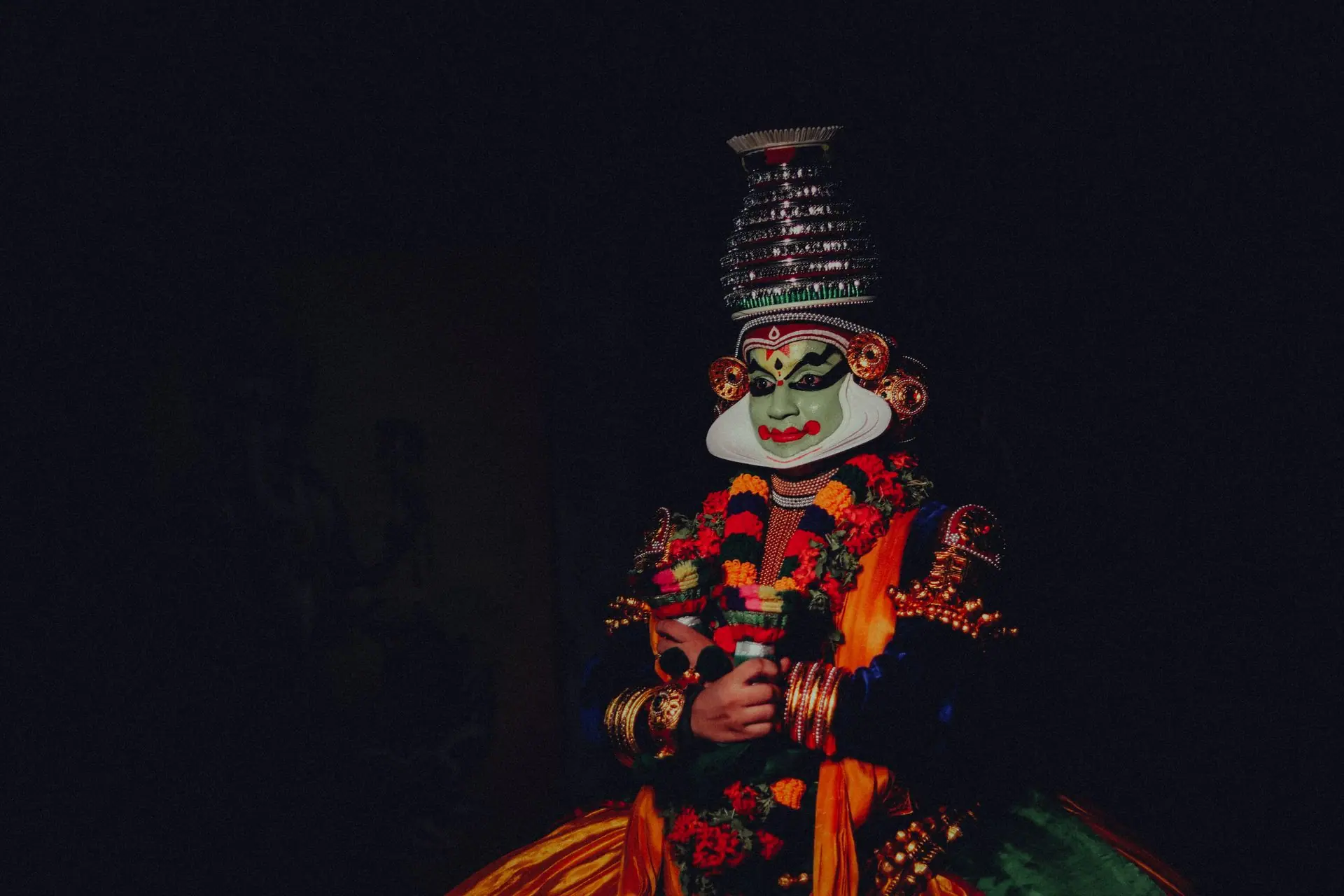 Colorful traditional Kathakali dancer with a distinctive mask on a black background