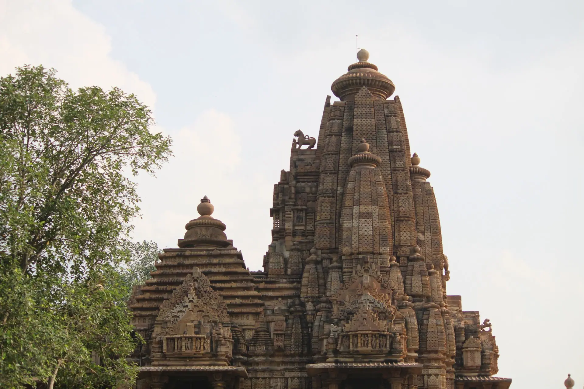 View of intricate stone carvings on a historic Khajuraho temple under a clear sky