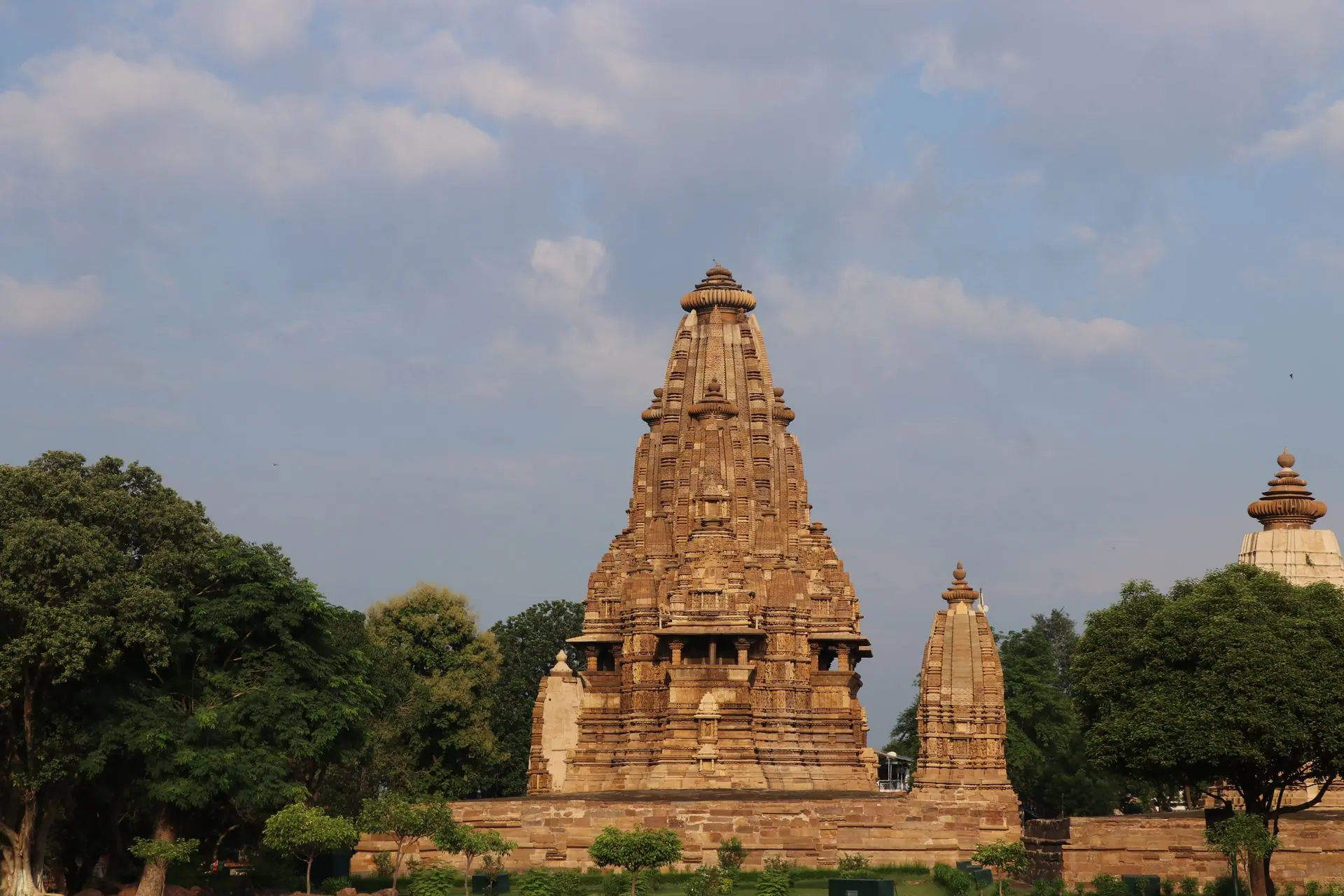 Stunning view of the ancient Khajuraho Temple surrounded by lush greenery under a blue sky