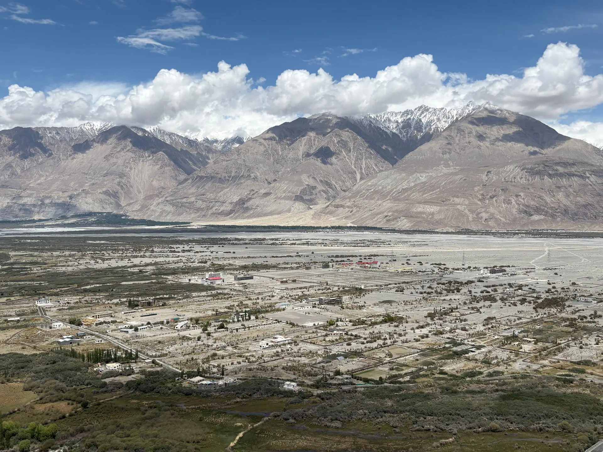 A stunning aerial view of Nubra Valley with mountains and scattered settlements beneath a blue sky