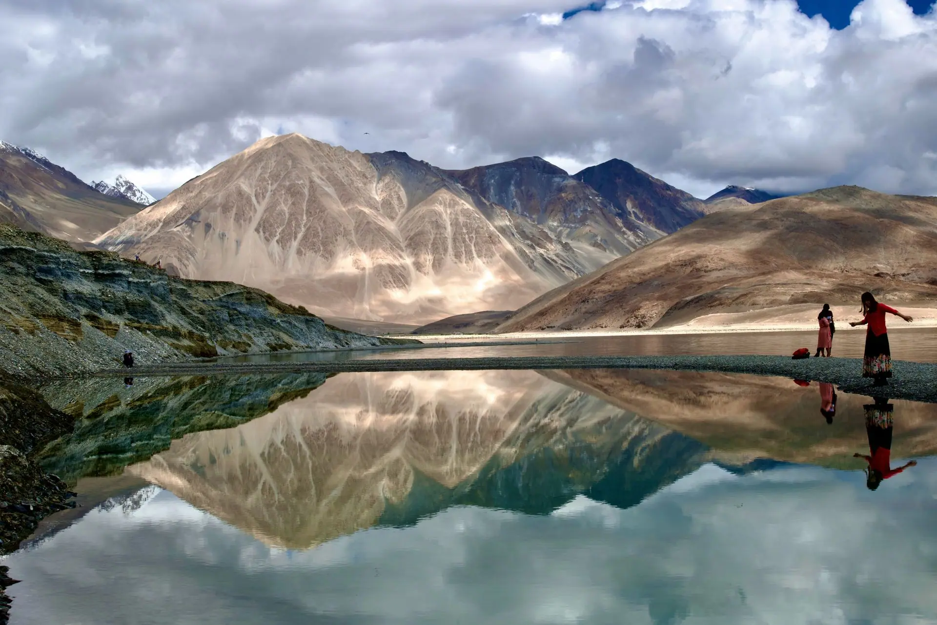 Captivating view of mountains and their reflection in Pangong Lake with people in the scene