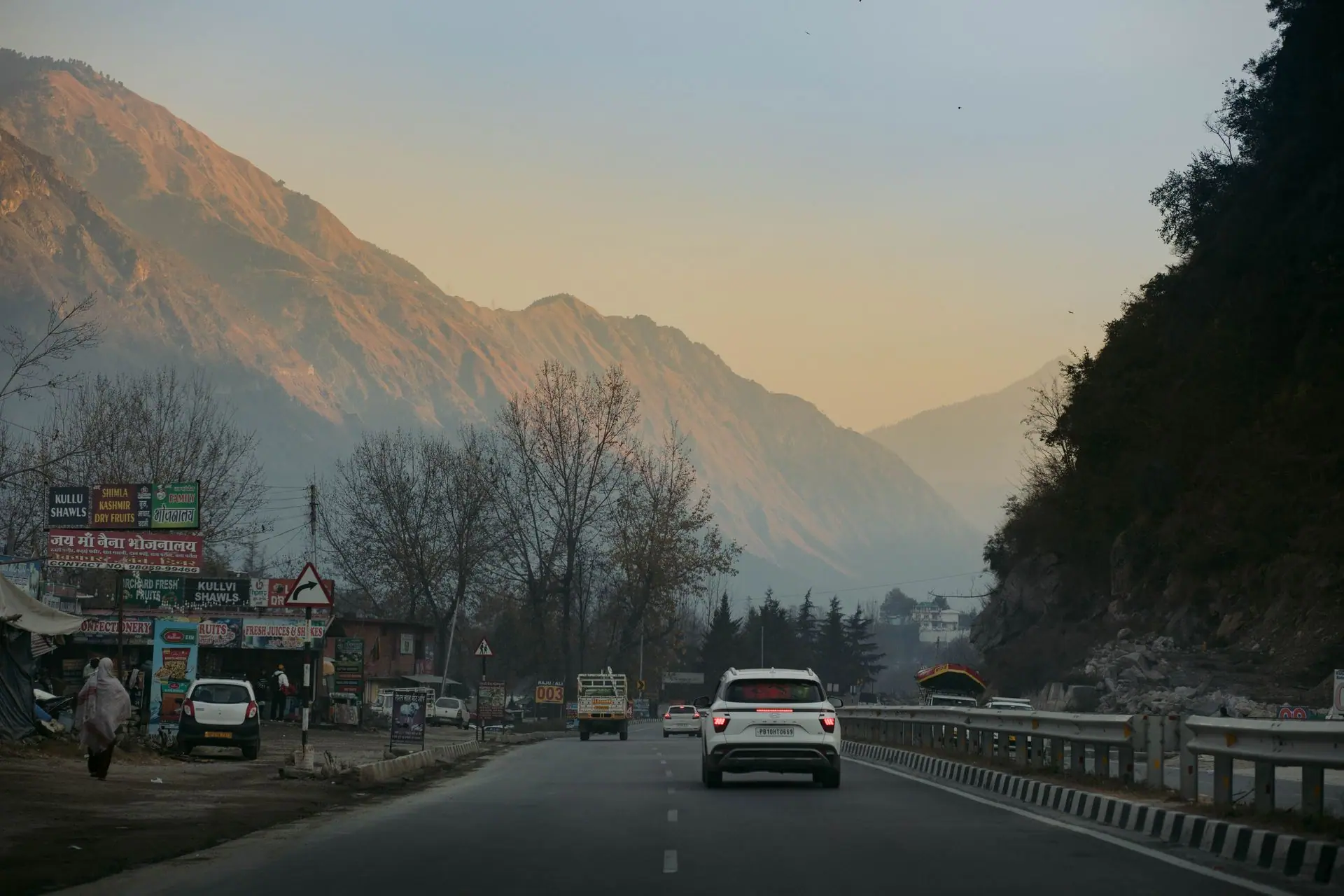 Captivating view of a highway through Kasol, Himachal Pradesh, with mountains at sunset