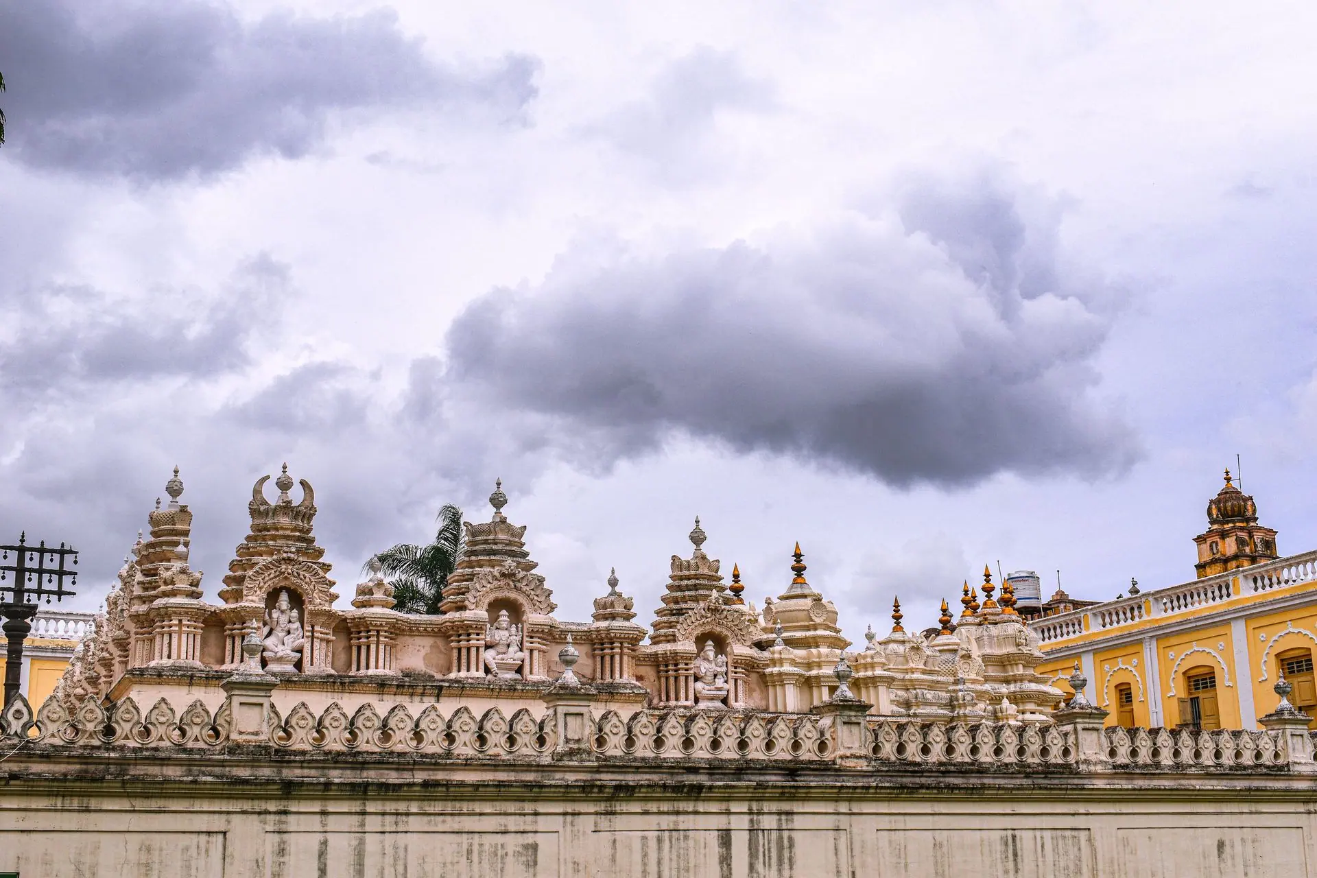 Intricate architectural details on the wall of Mysore Palace, India, under a cloudy sky