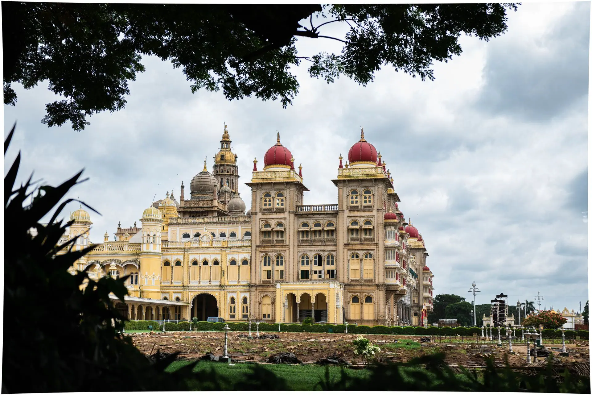 Stunning daytime view of Mysore Palace with lush greenery and cloudy sky