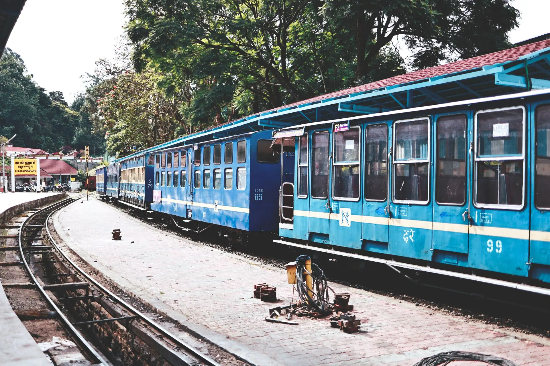 Scenic view of a blue train at Ooty Railway Station amidst lush greenery