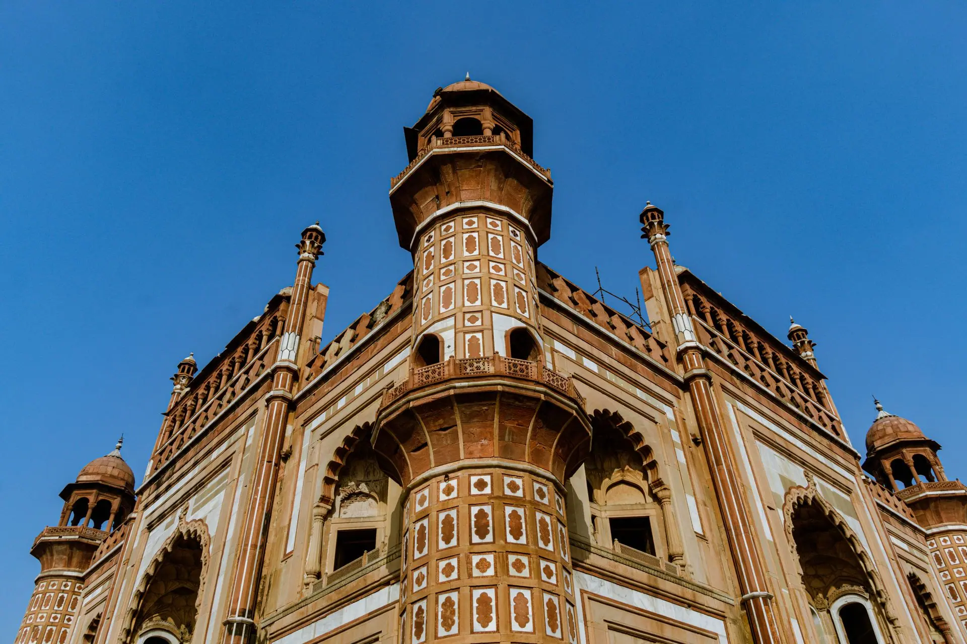 Low-angle shot of Safdarjung Tomb with intricate detailing under a clear blue sky in New Delhi, India