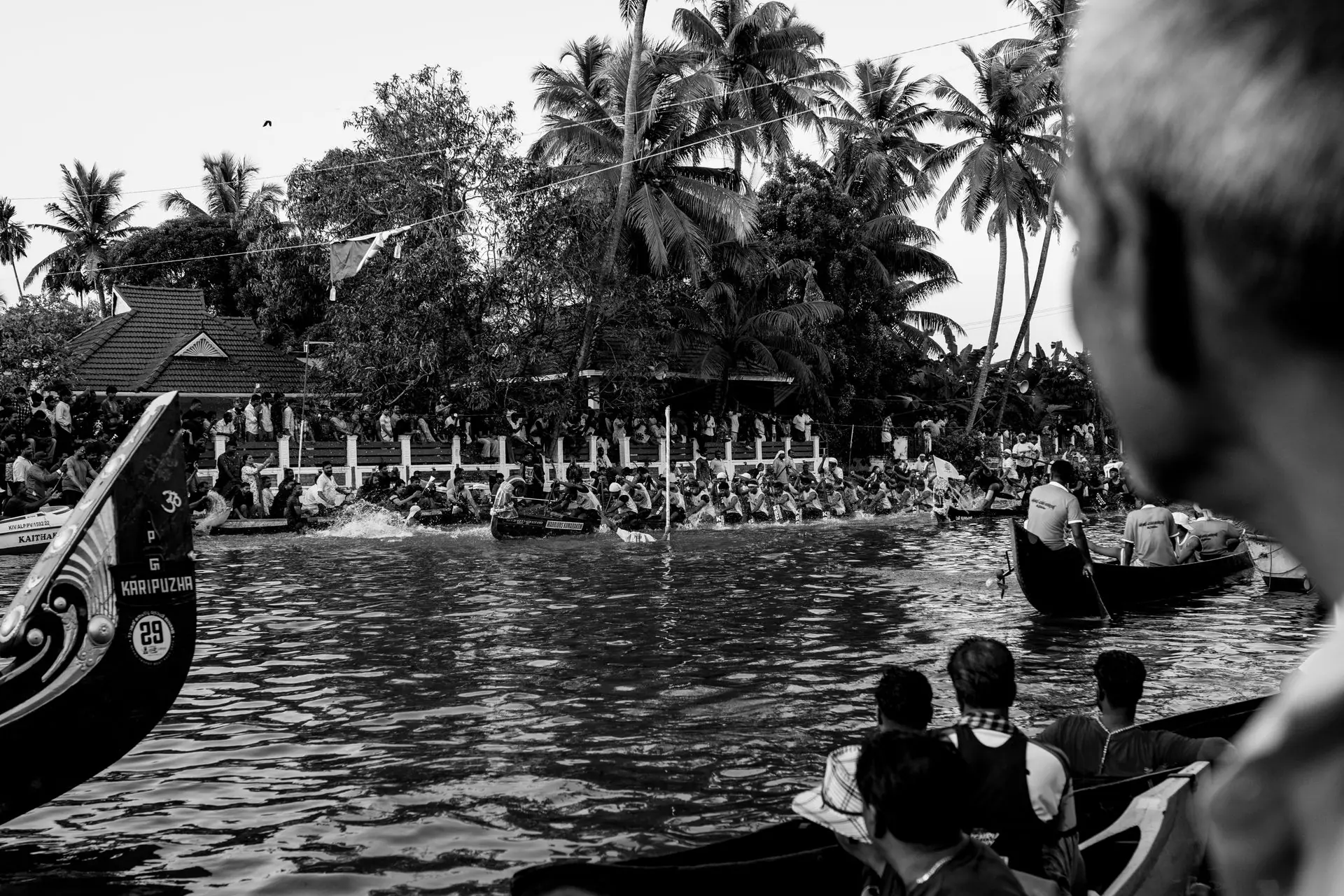 Black and white photo of a vibrant snake boat race in Kumarakom, attracting a large crowd