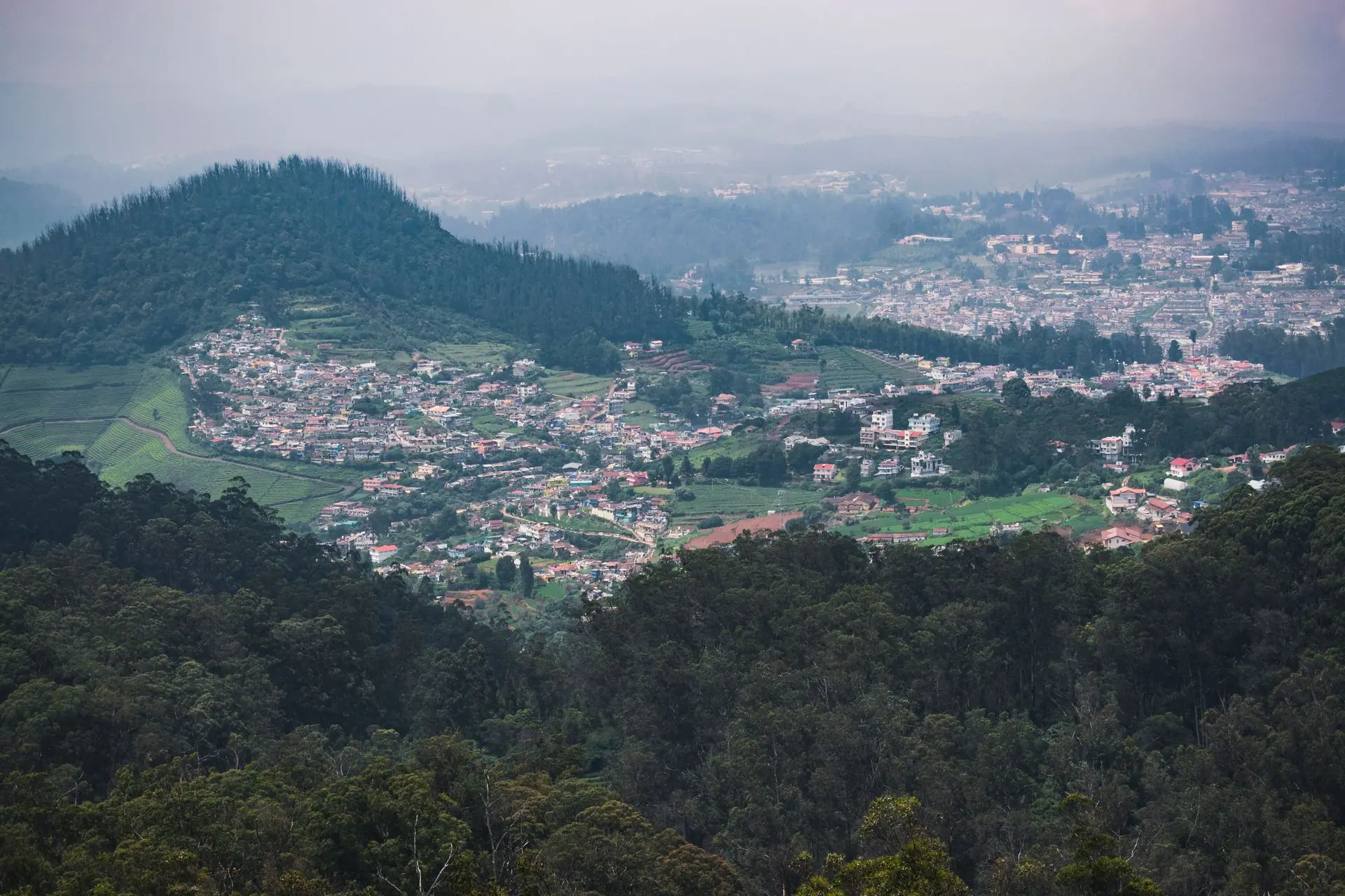Aerial view of lush Ooty hills and townscape surrounded by verdant forests
