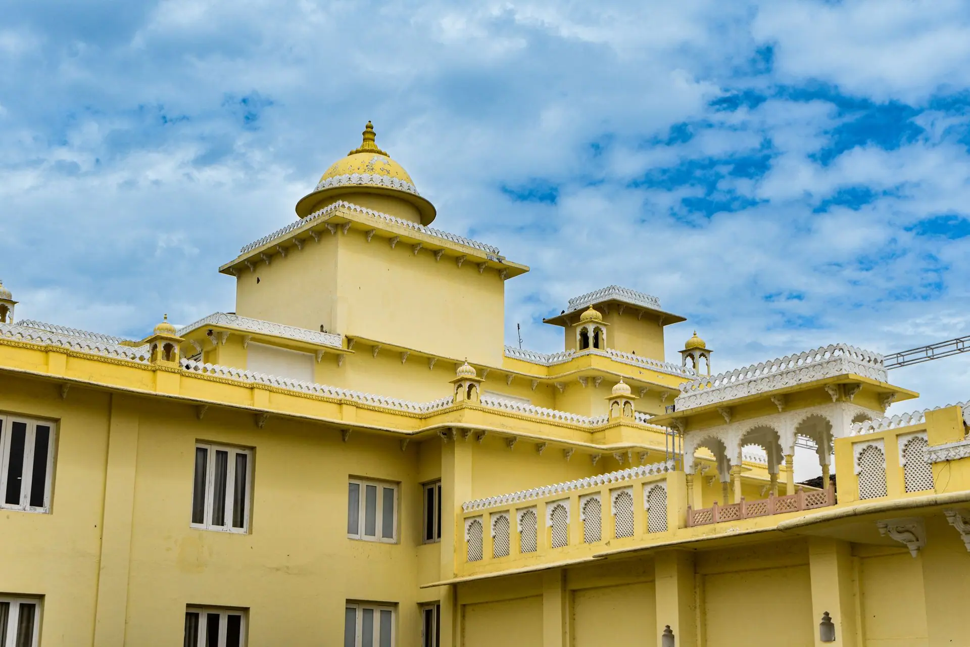 Elegant yellow facade of a historic palace in Udaipur against a vibrant sky