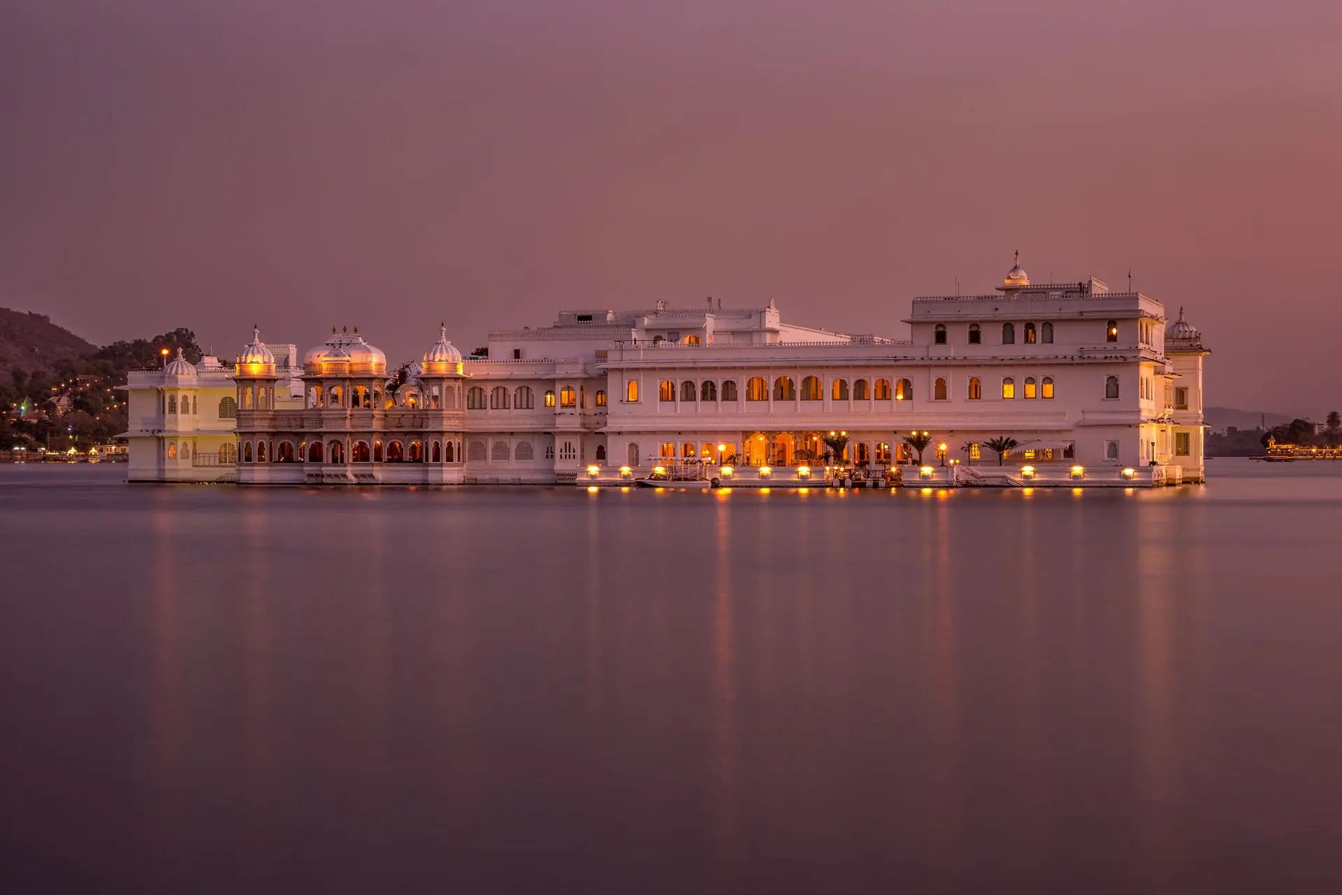 Stunning twilight view of Udaipur's Lake Palace illuminated, reflecting serene lake vibes