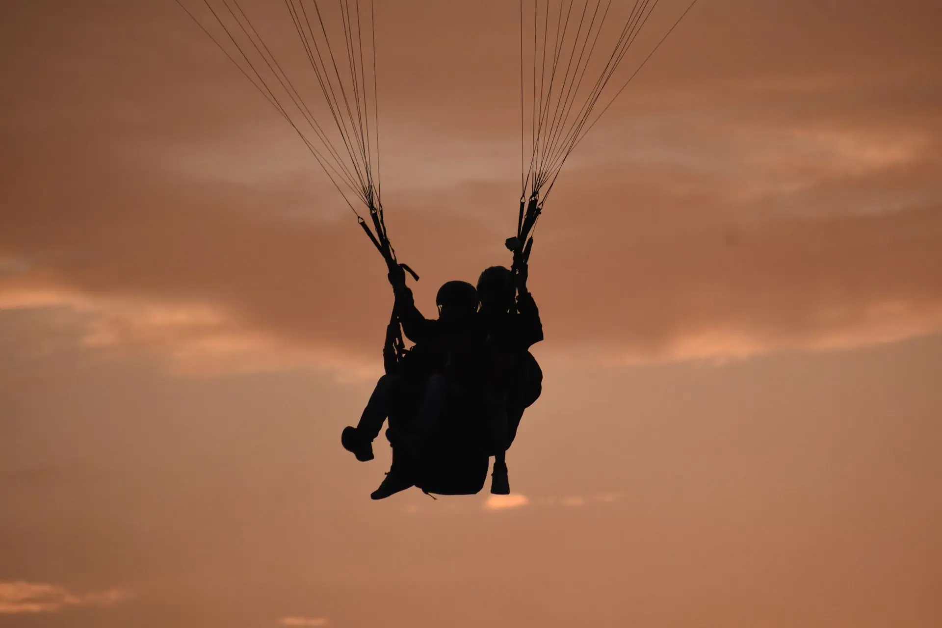 Silhouette of two people paragliding against a vibrant sunset sky in Bir, India