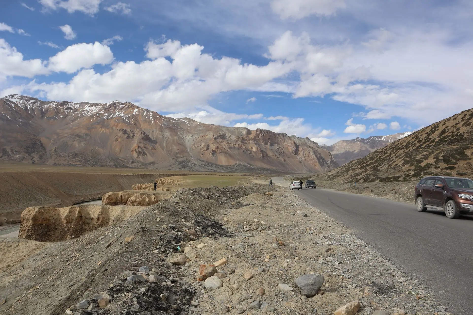 A stunning view of a mountain road in Ladakh, with cars and rugged landscape