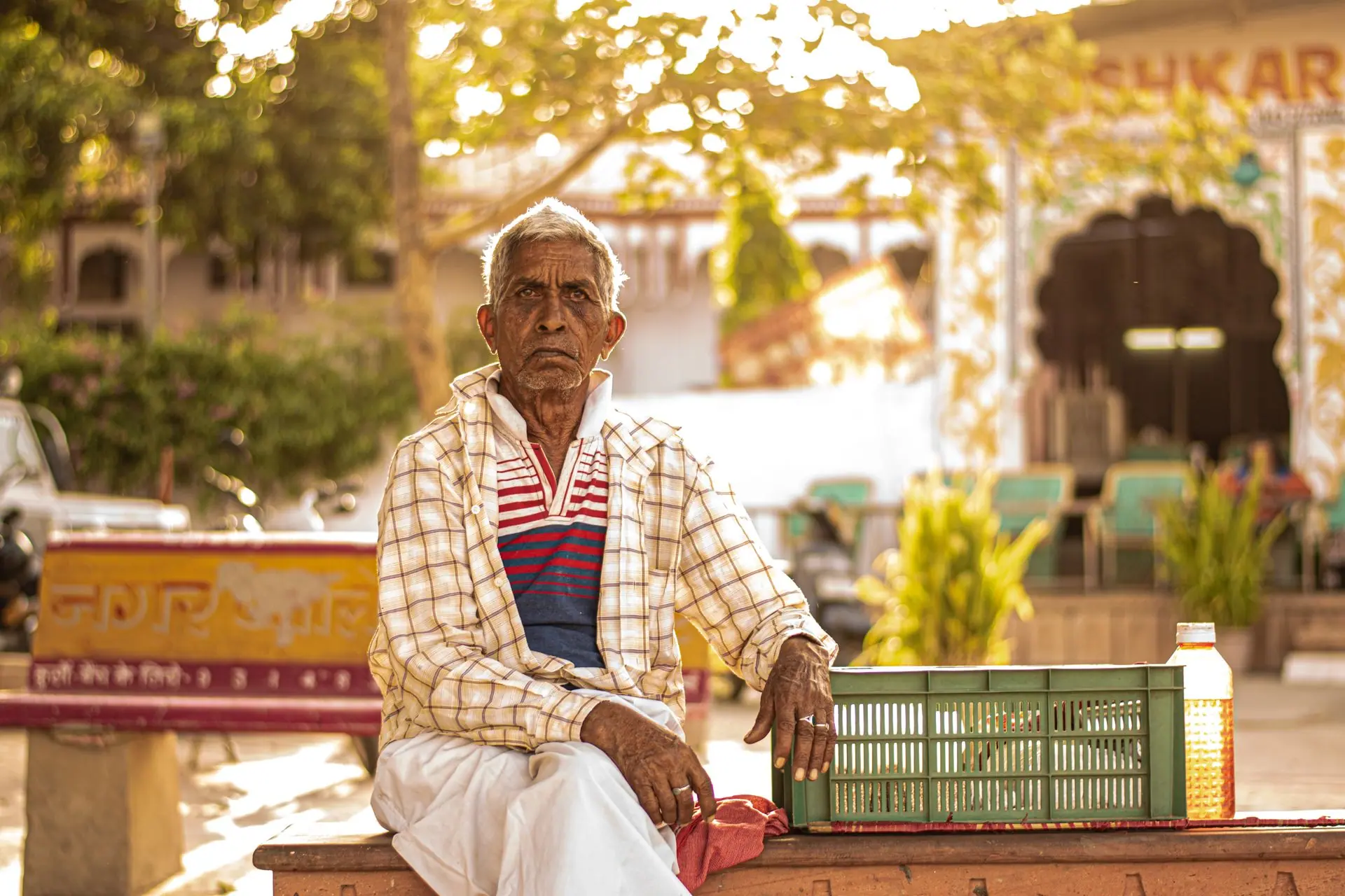Elderly man in Pushkar, India sitting on a bench in a market setting during daytime