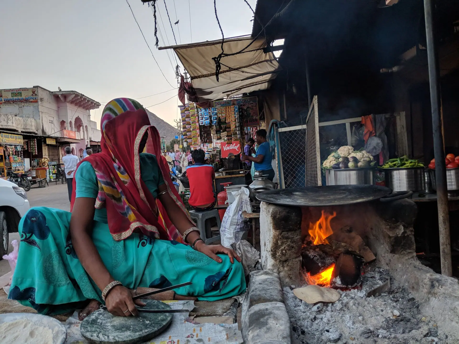 Woman preparing food on open flame at a bustling Jaipur street market