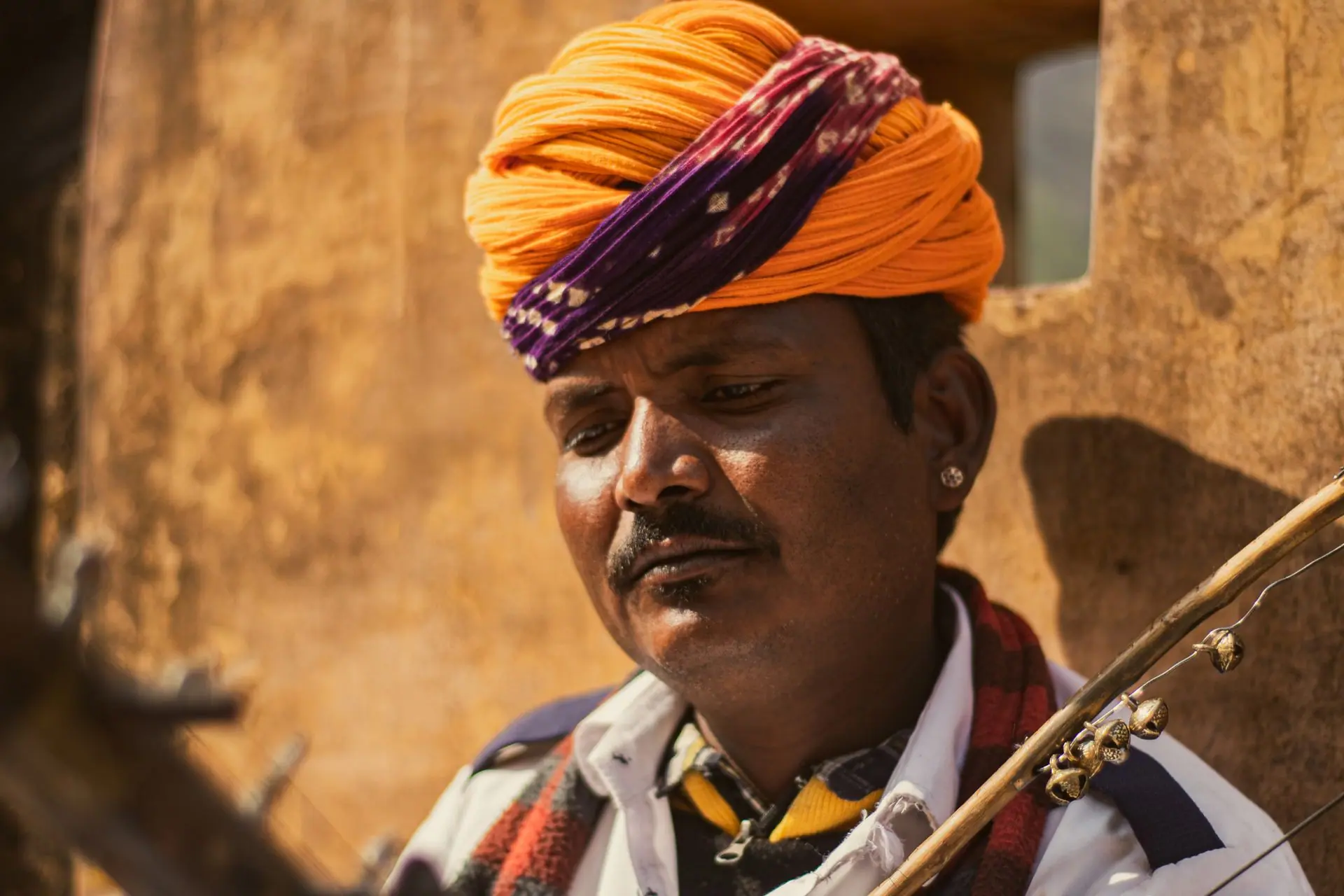 Portrait of a Rajasthani musician in colorful turban playing an instrument outdoors in India
