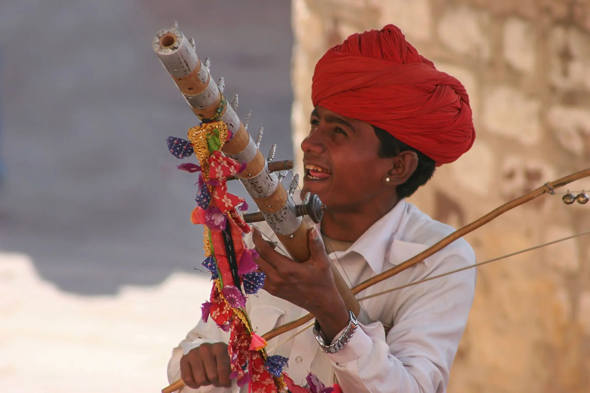 A Rajasthani musician plays a colorful traditional instrument outdoors