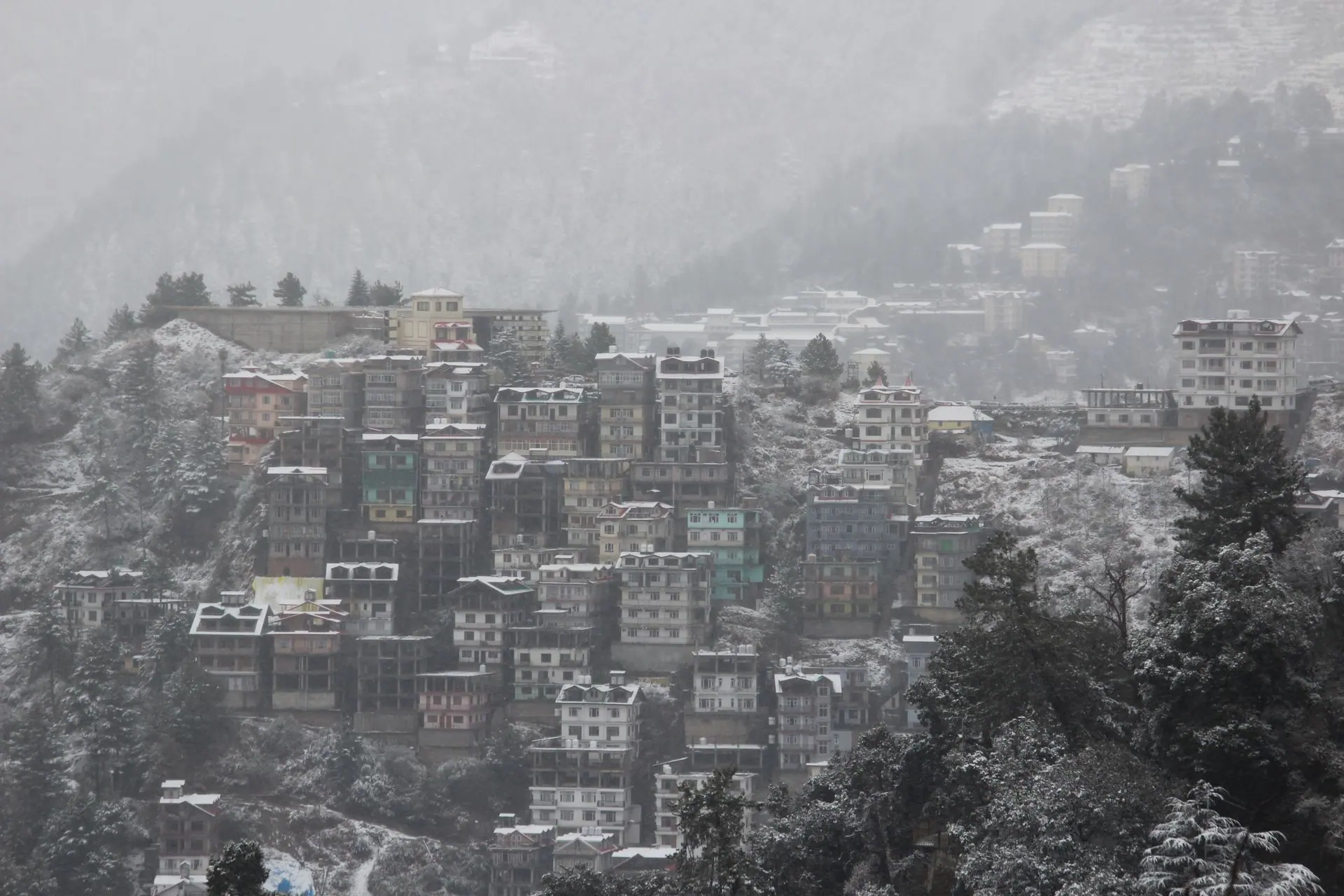 Scenic winter view of snow-covered buildings nestled in Shimla's hills, Himachal Pradesh, India