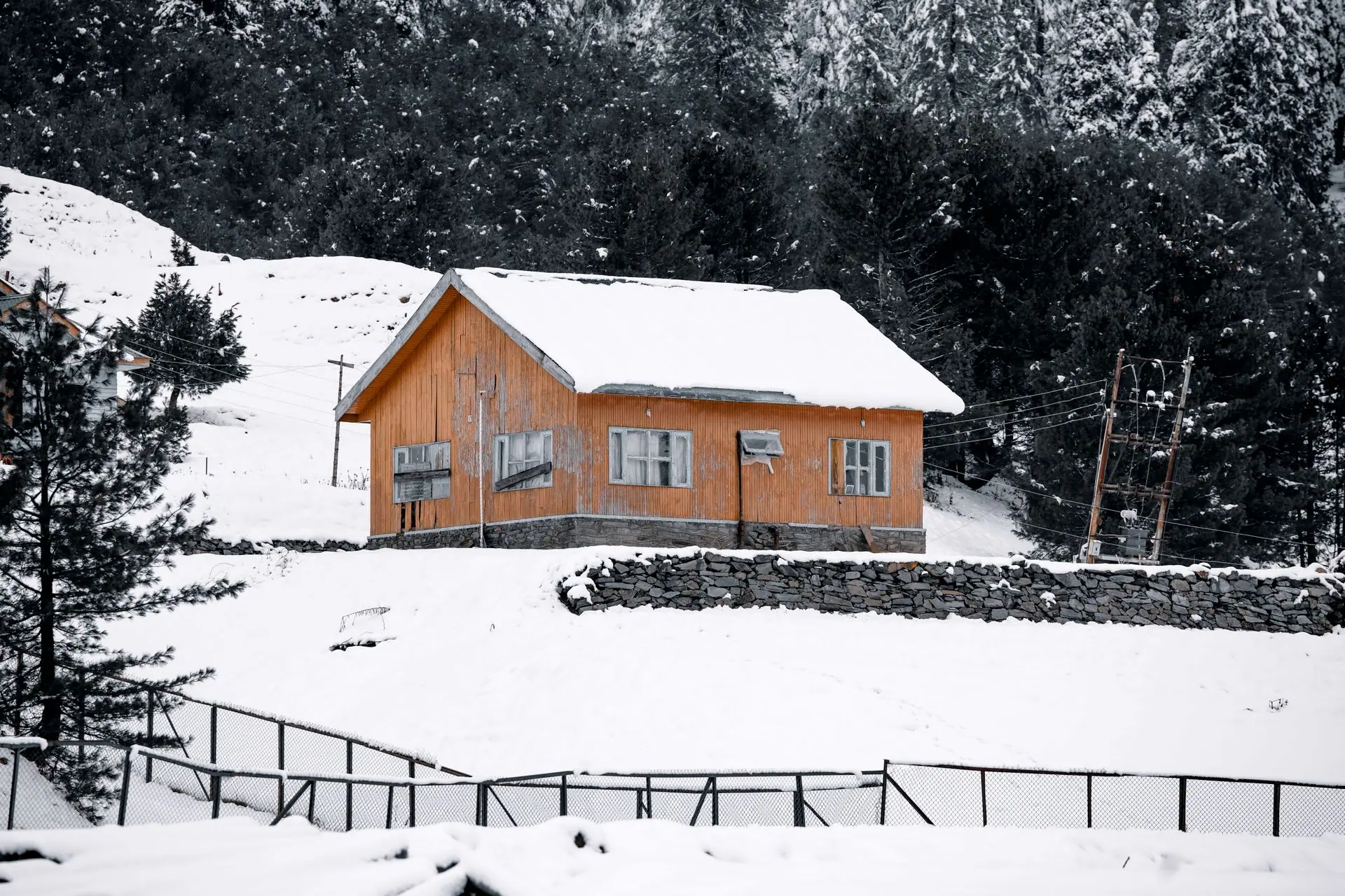 A serene winter scene of a snow-covered cabin surrounded by pine trees in Gulmarg