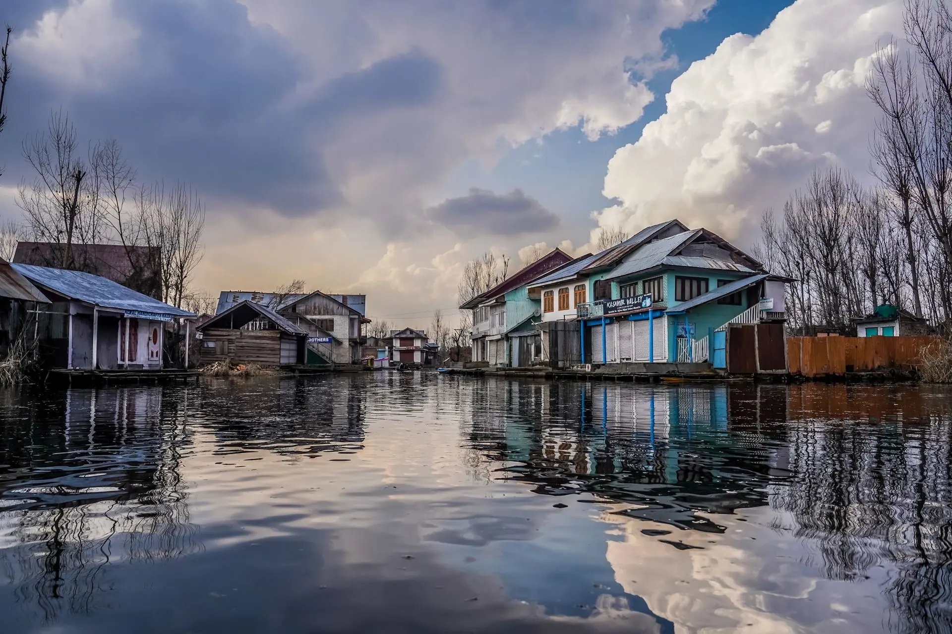 Picturesque view of traditional houses by Dal Lake in Kashmir under dramatic clouds